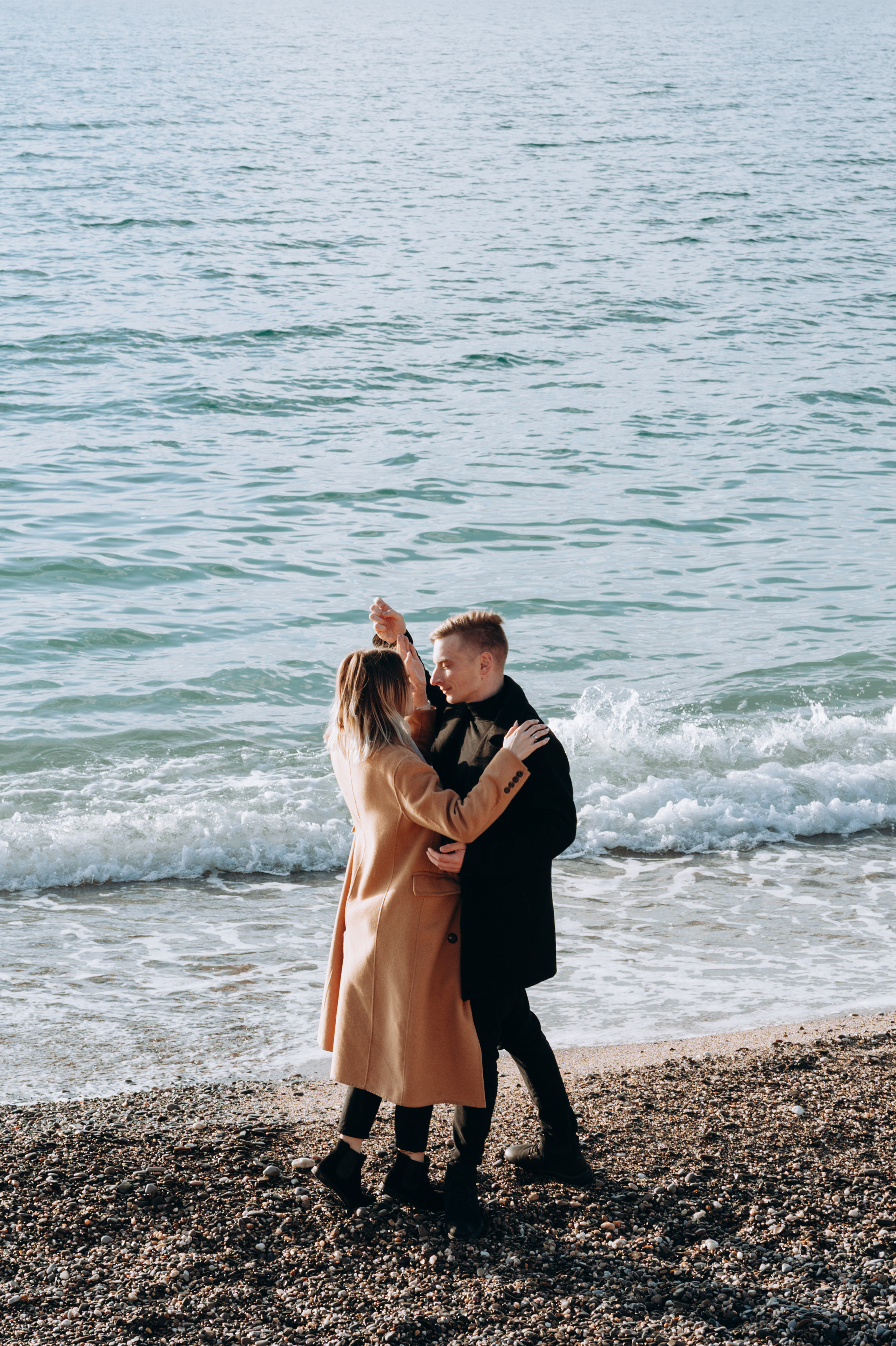 Танец девушки и мужчины на берегу моря зимой