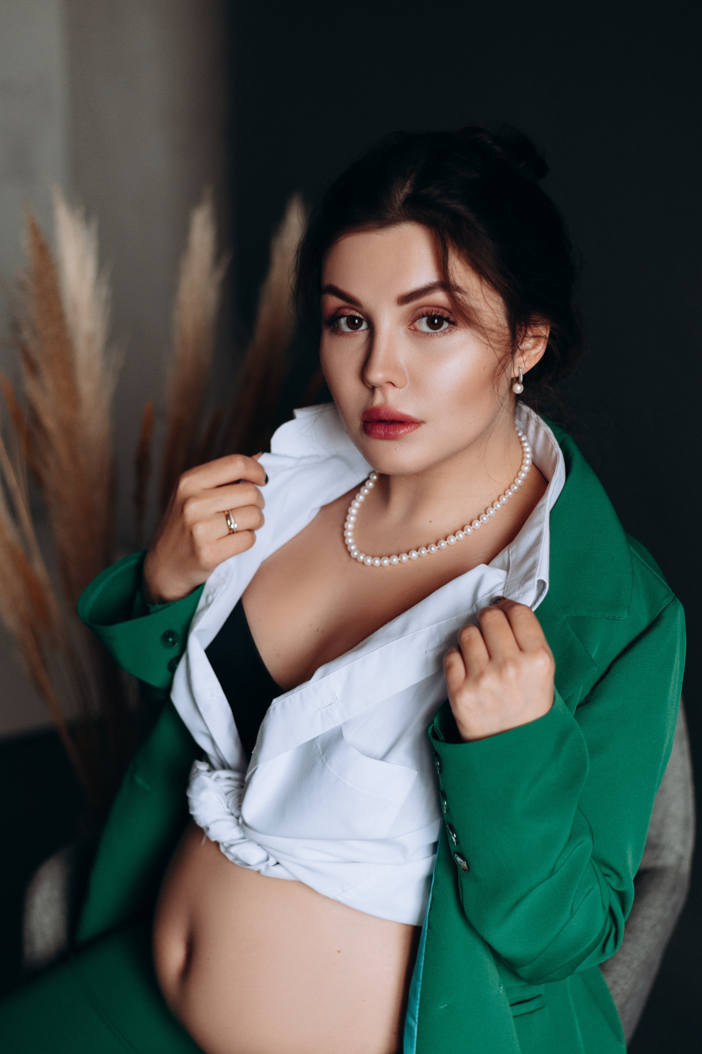 Портрет беременной девушки в студии в зеленом брючном костюме