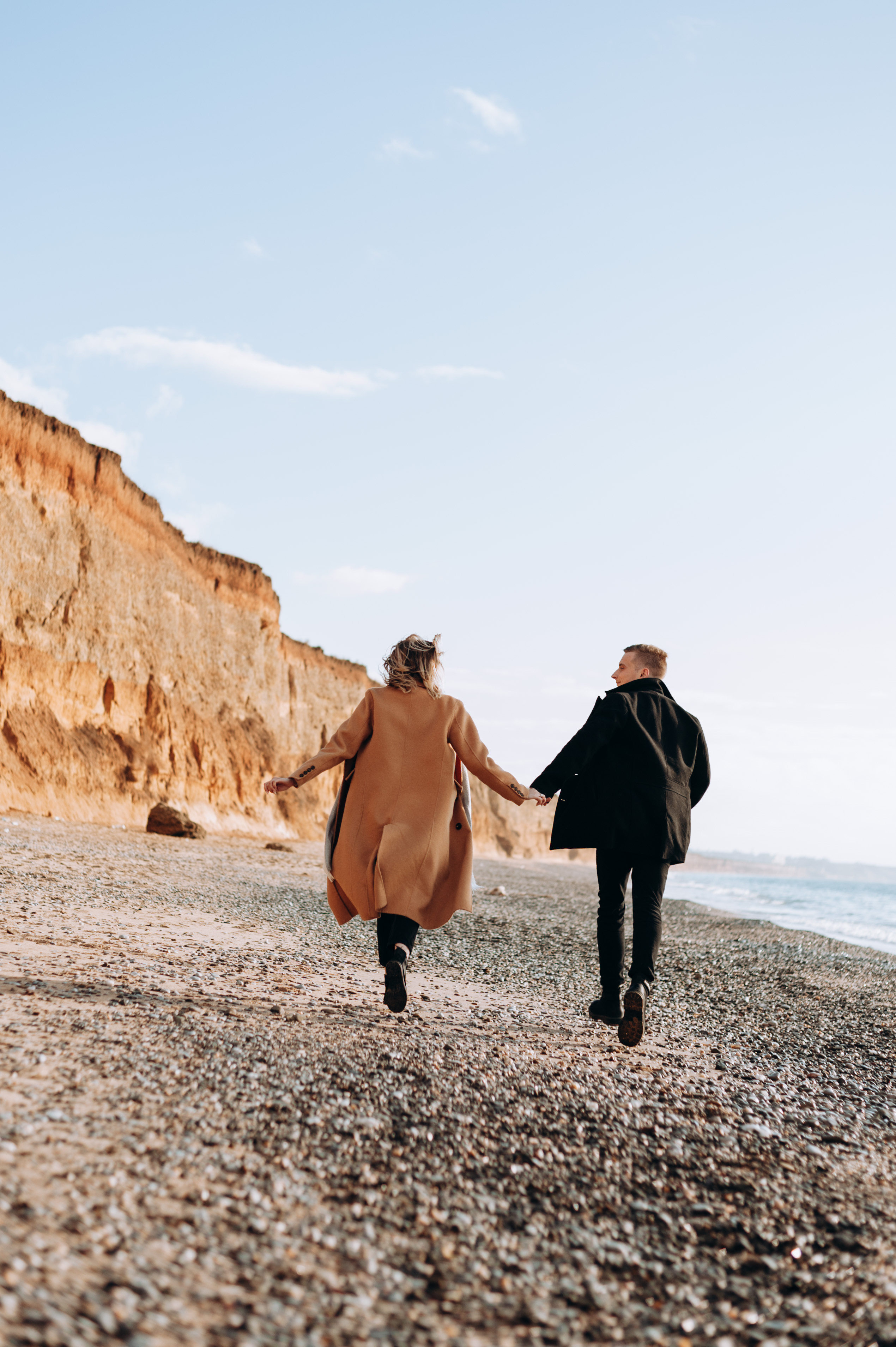 Парень и девушка бегут по пляжу на берегу моря