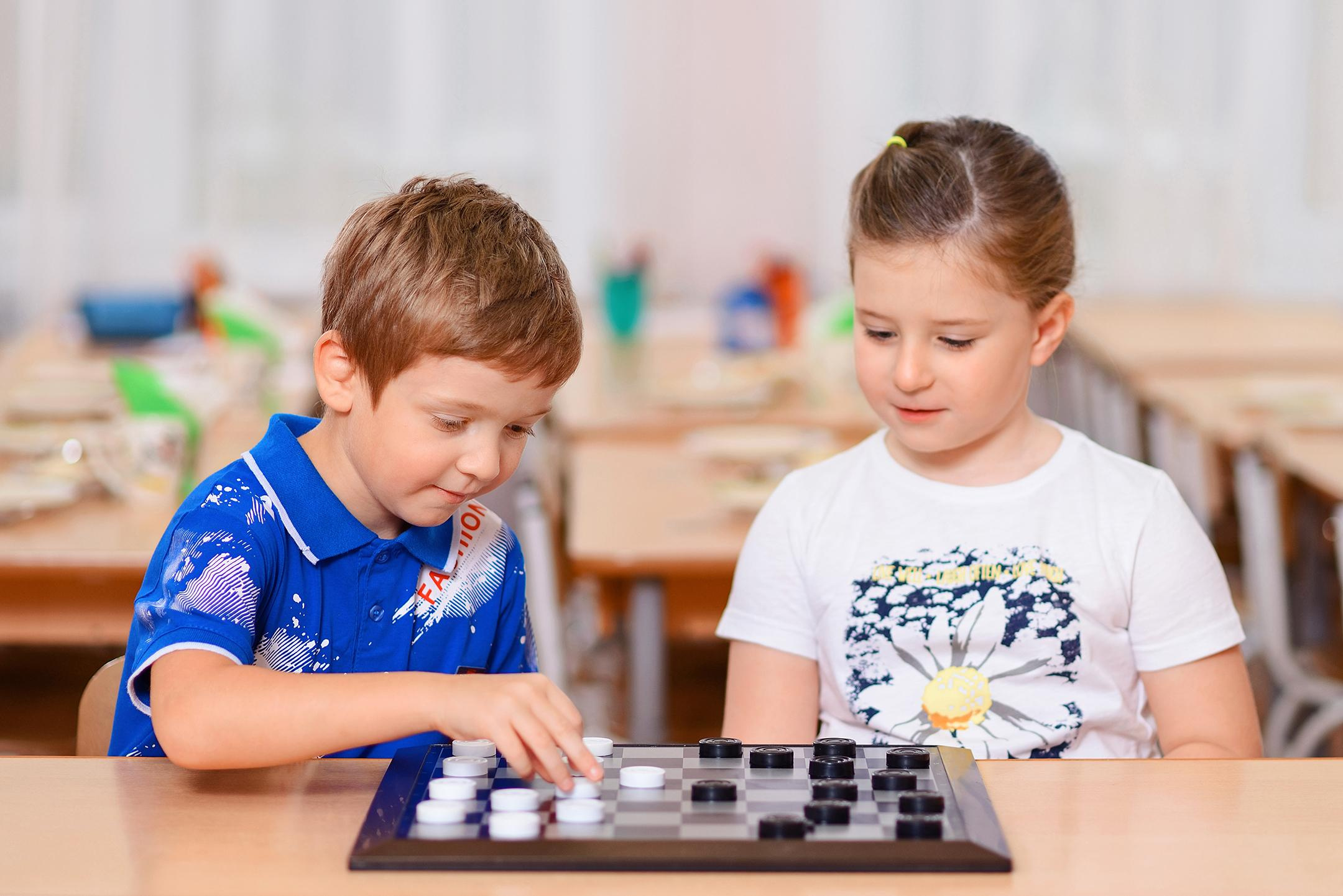 Портрет мальчика и девочки, играющих в шашки, для выпускного альбома детского сада