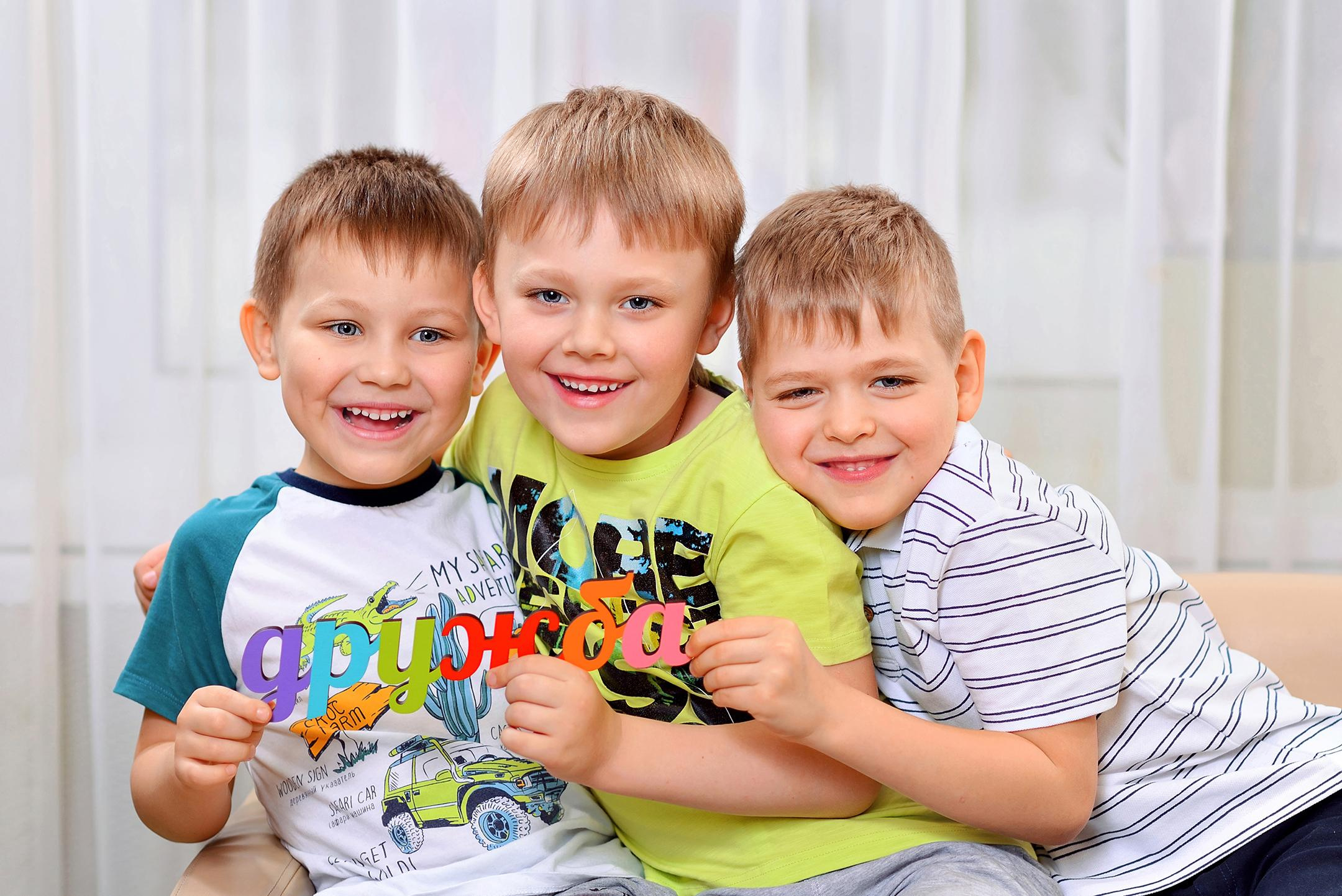 Обнимающиеся мальчишки-друзья держат табличку "Дружба"