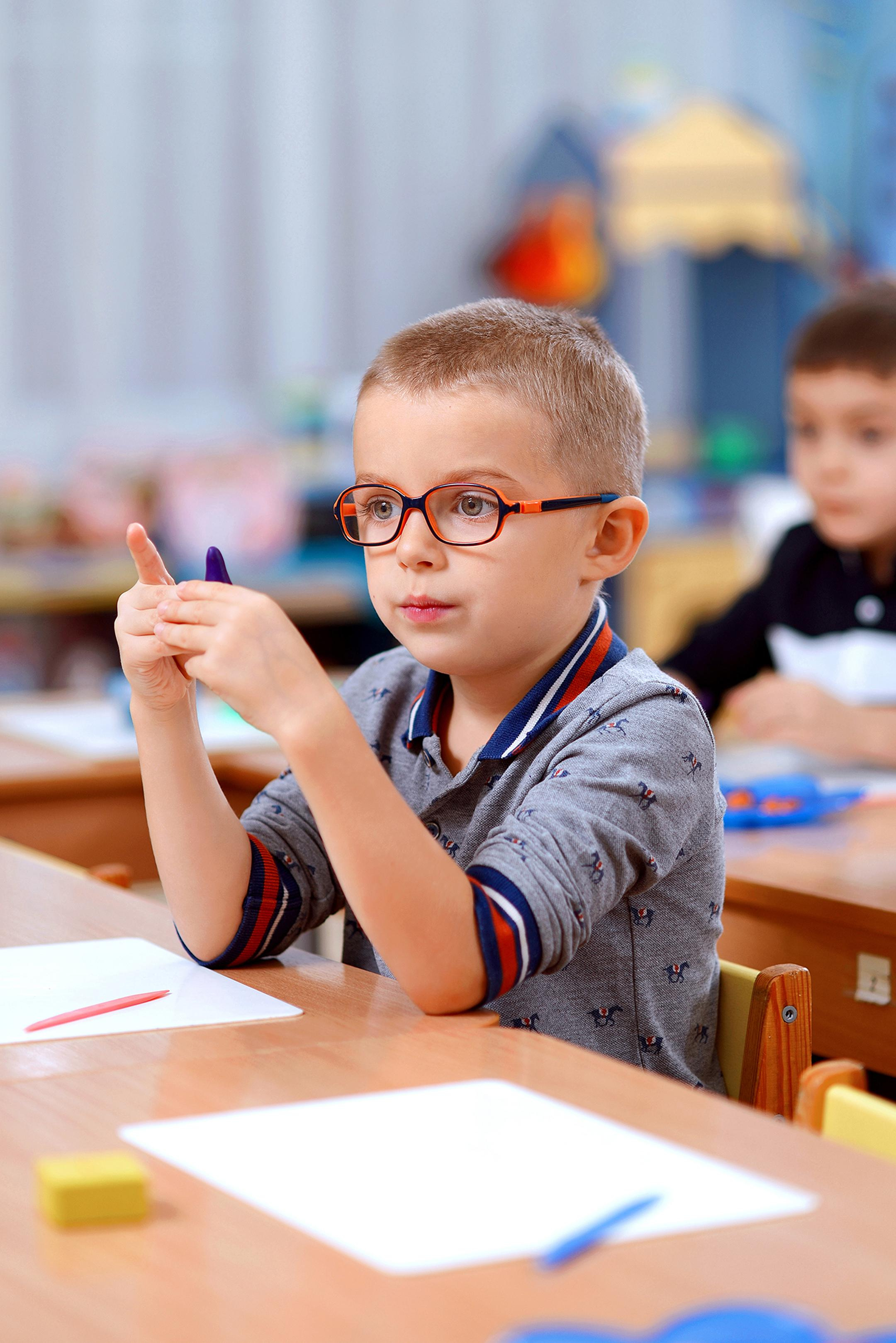Мальчик в очках на занятии в детском саду по лепке