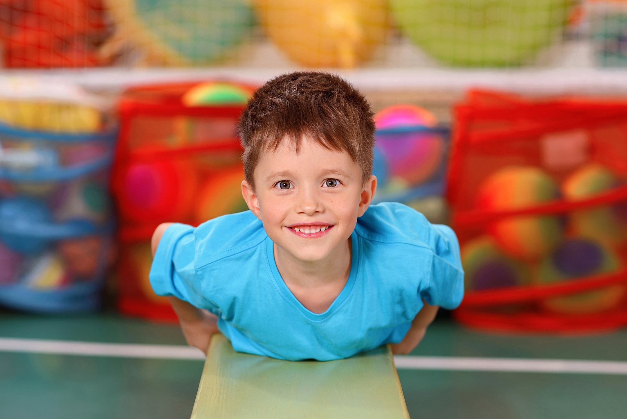 На физкультуре в детском саду мальчик ползёт по скамейке