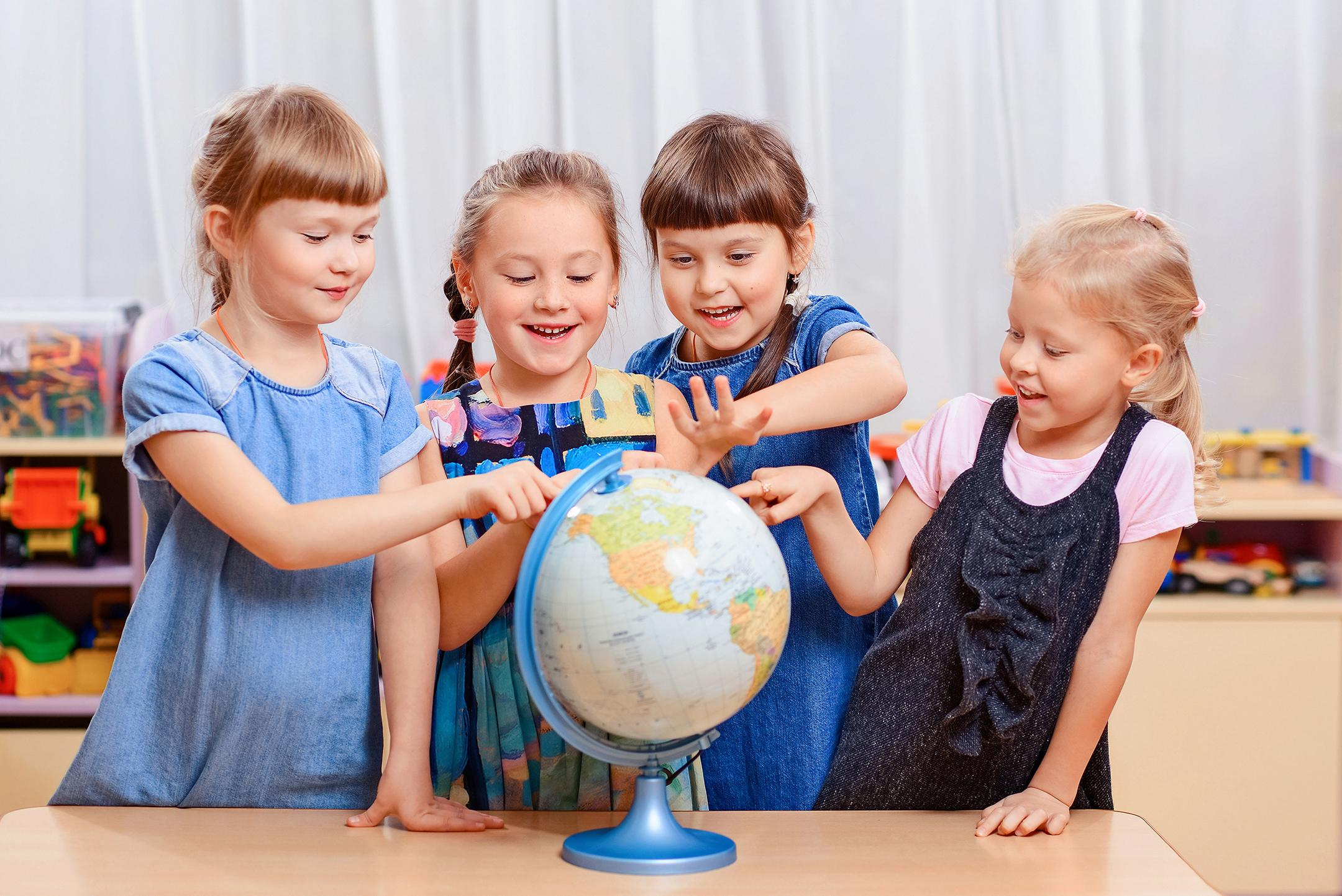 Дети в детском саду играют с глобусом