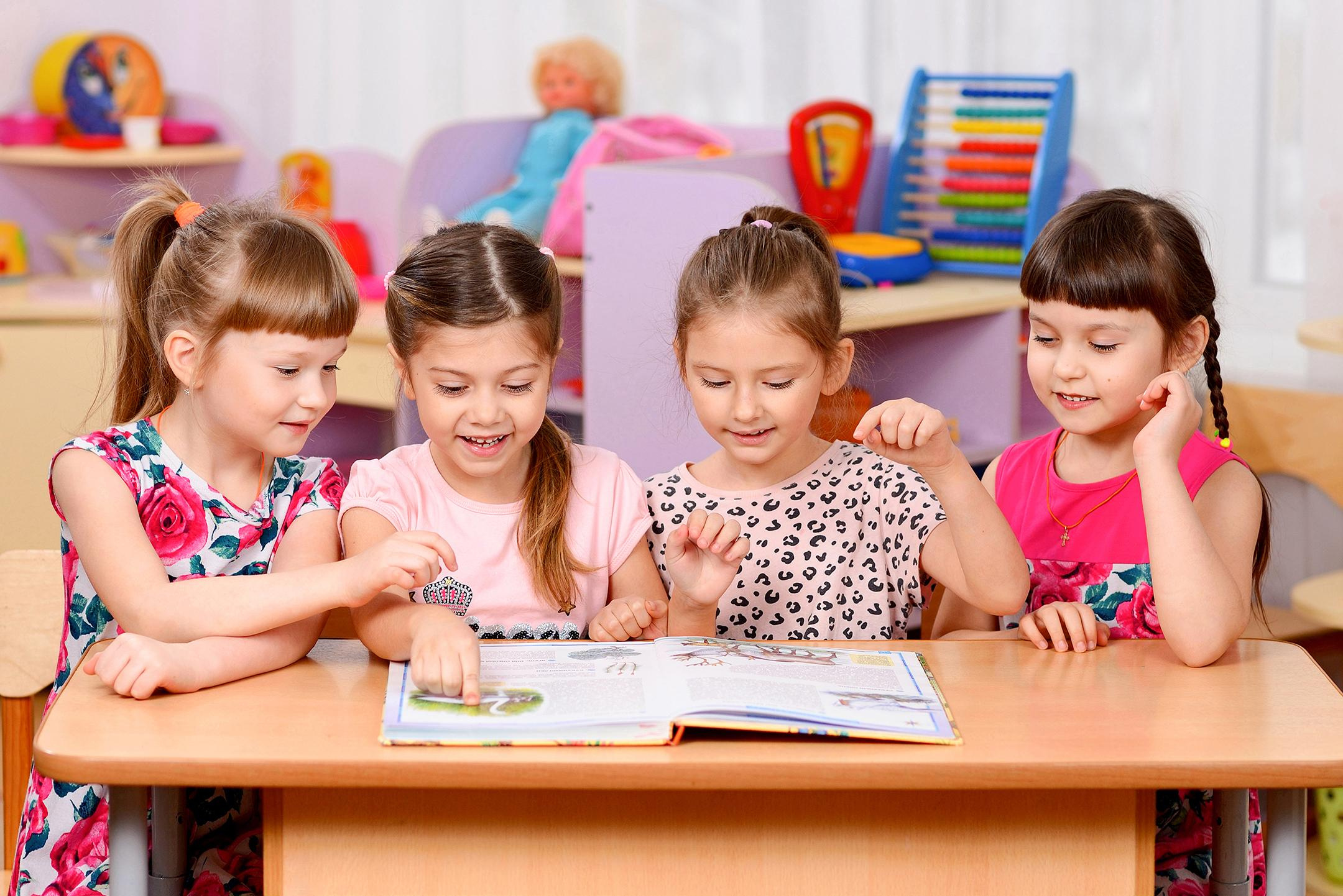 Фото детей в детском саду, читающих книгу за столом