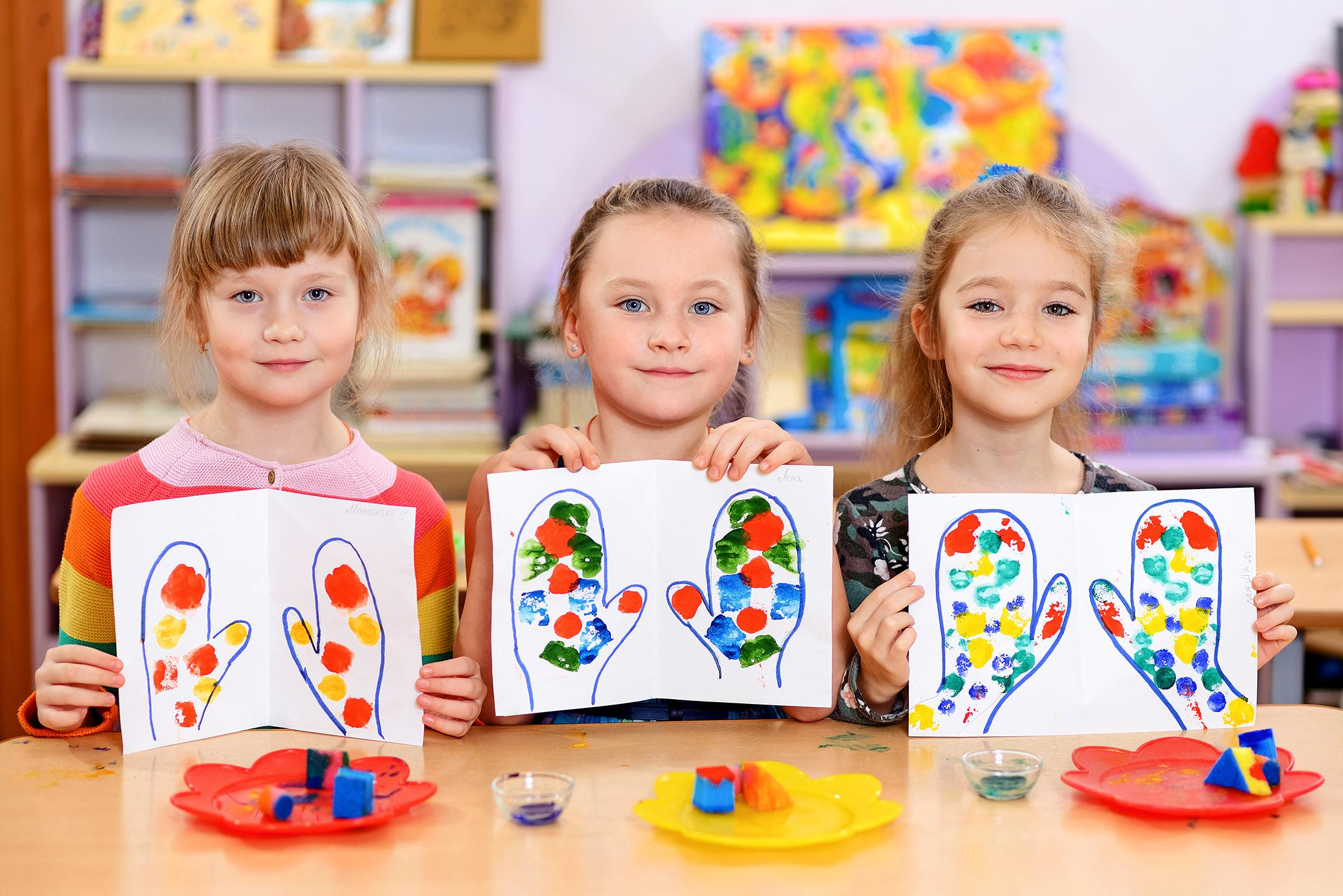 Дети в детском саду показывают свои рисунки