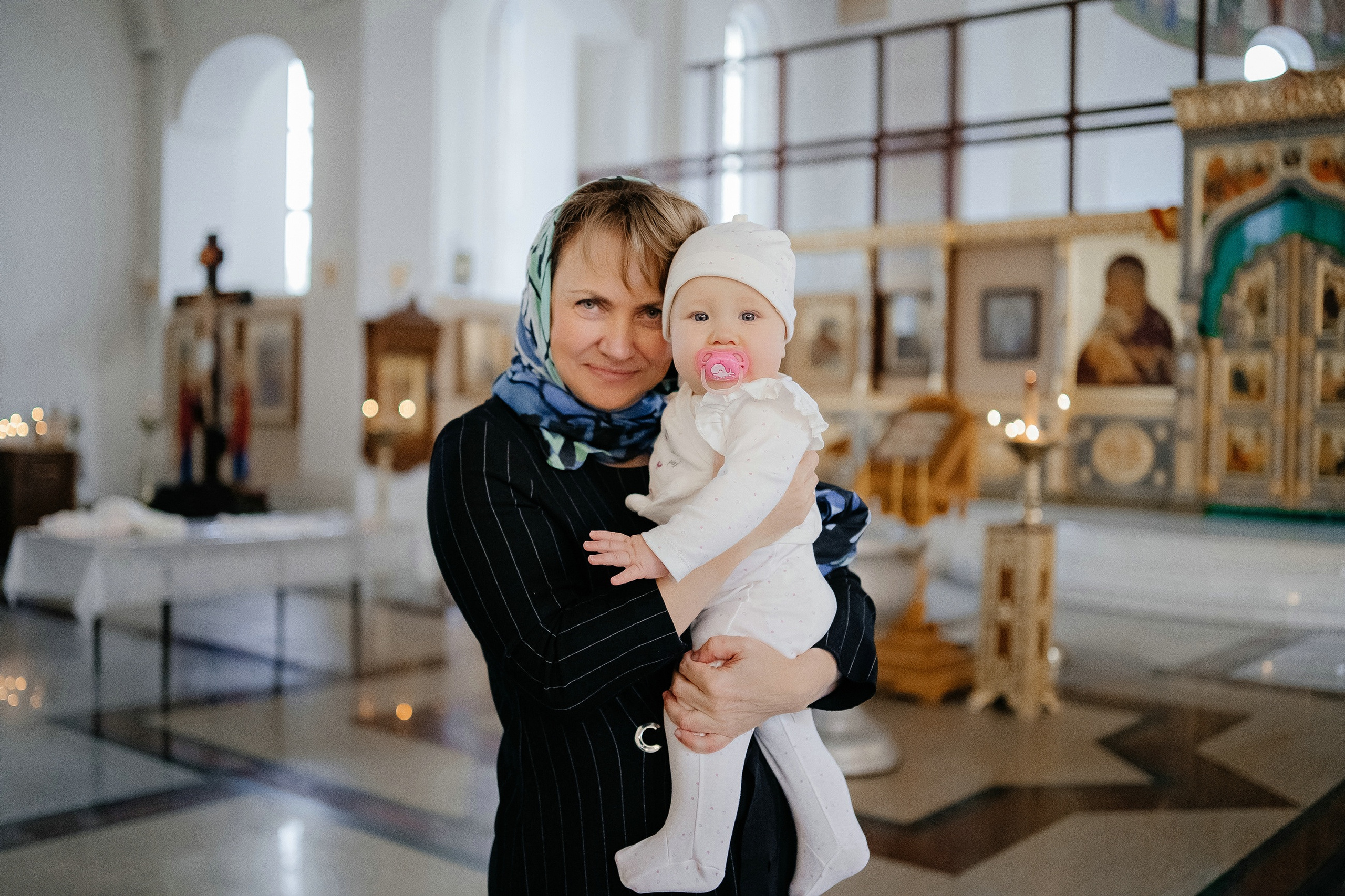 Бабушка на крестинах ребенка в храме.