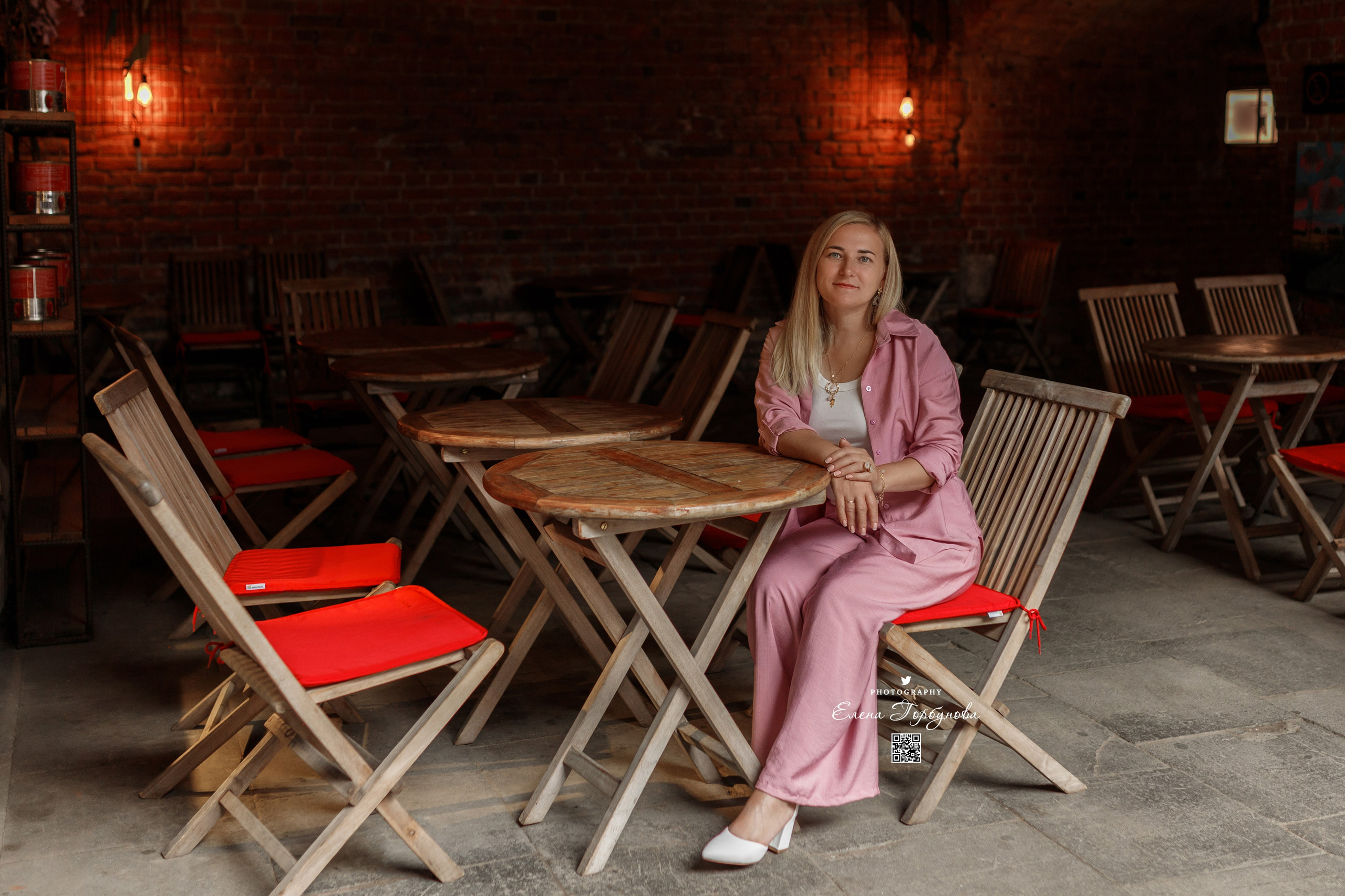 девушка сидит за столиков в кафе в атмосферном кирпичном месте