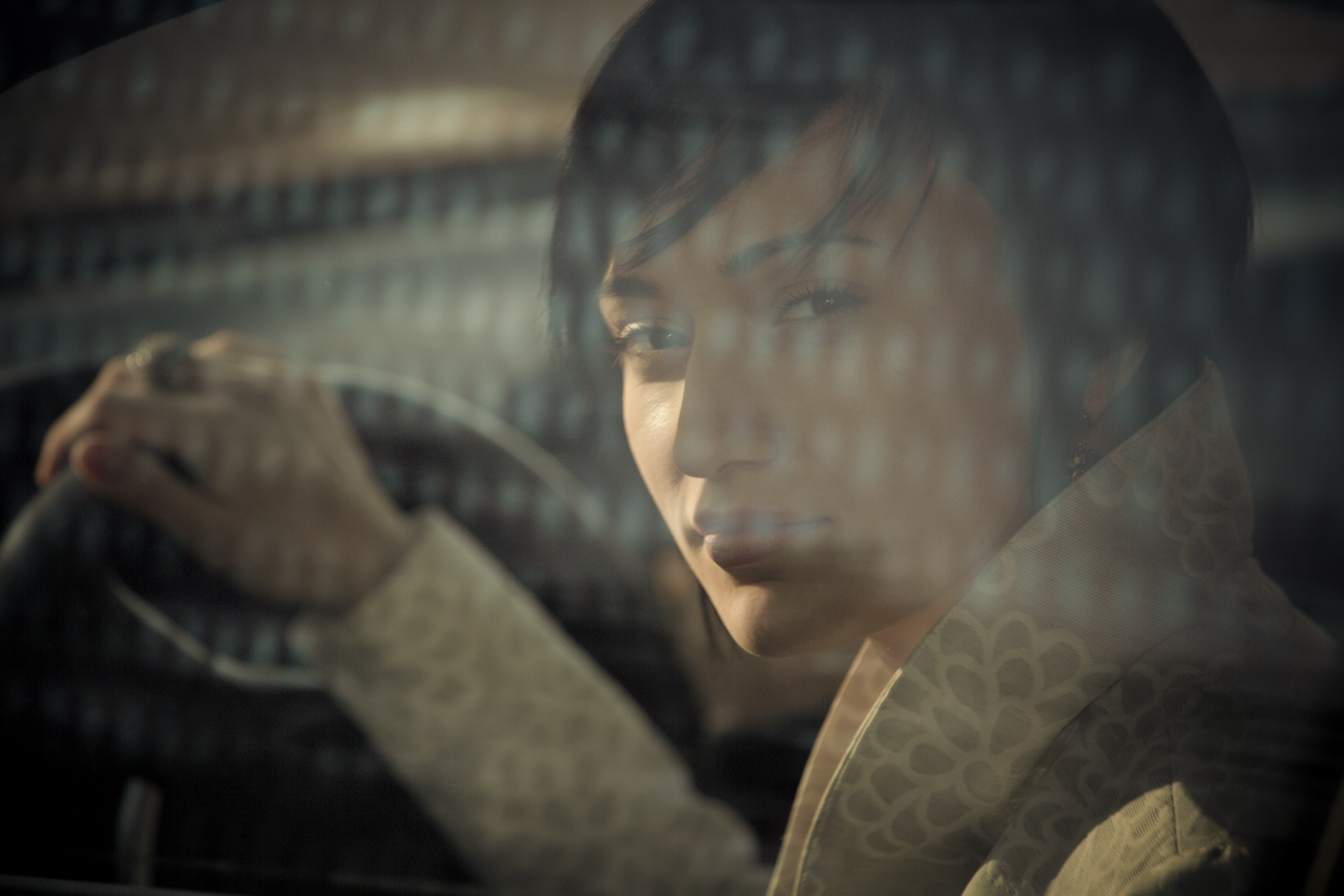 Девушка в элегантном пальто сидит за рулем современного автомобиля, сочетая классический стиль и динамичную жизнь.