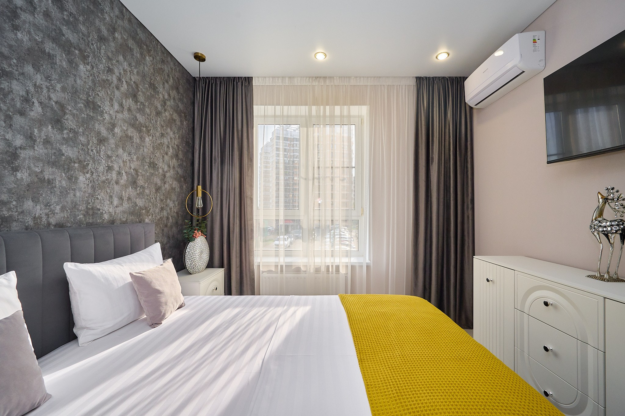 комната серая стена серая кровать темные шторы белая тумба телевизор 