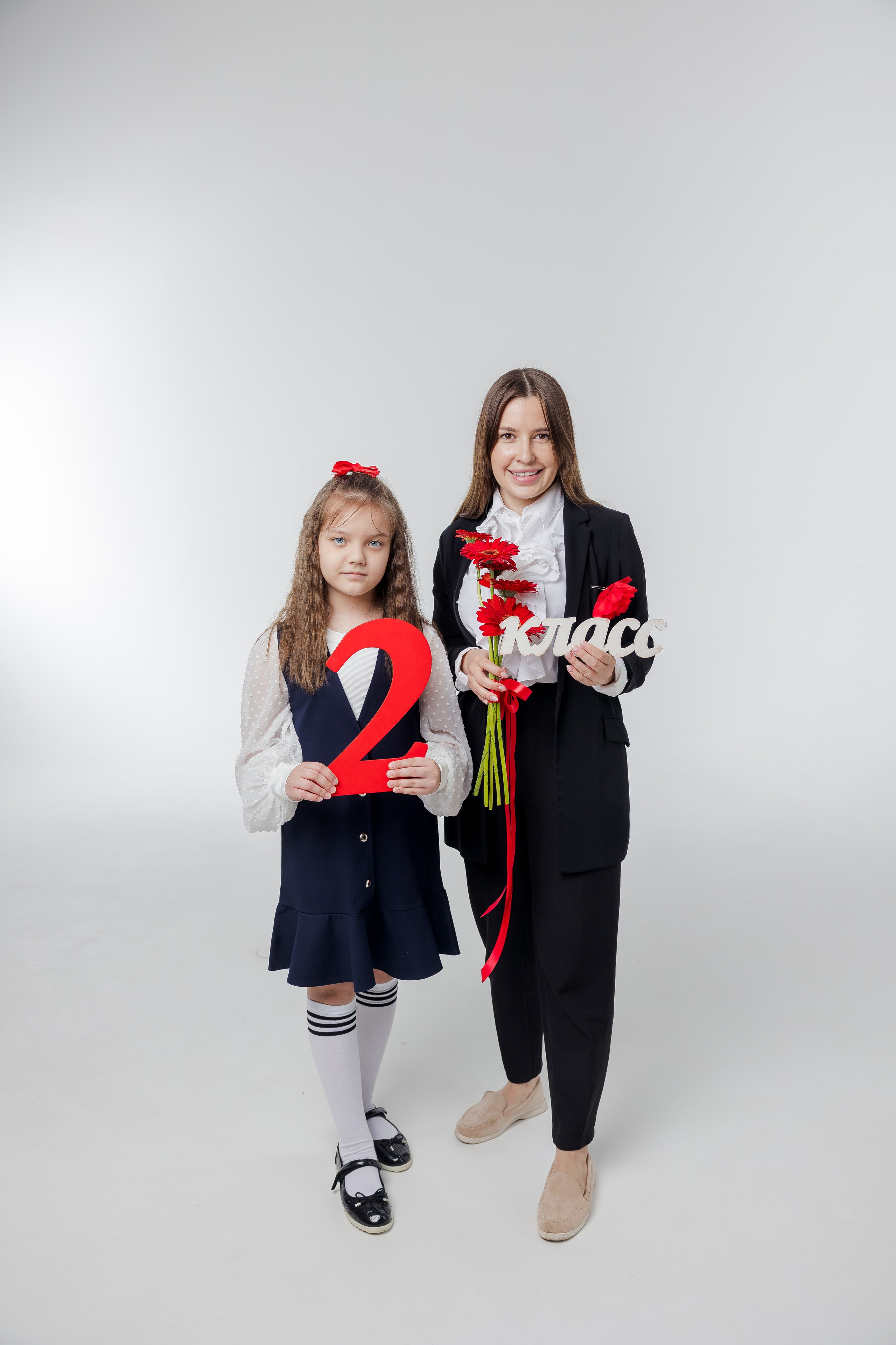 Девочка стоит с учителем с надписью 2 класс