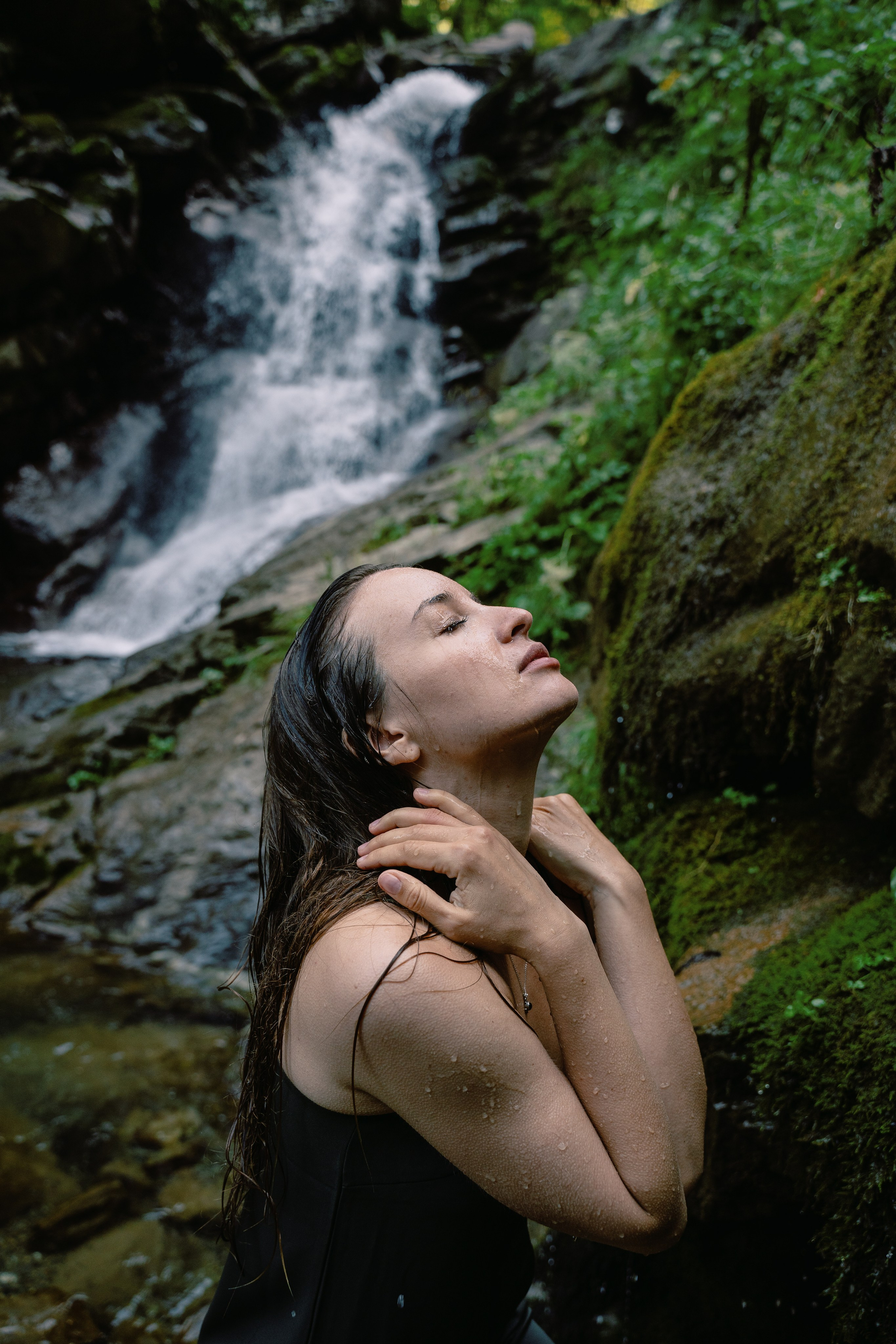 Портретный фотоснимок девушки на фоне водопада