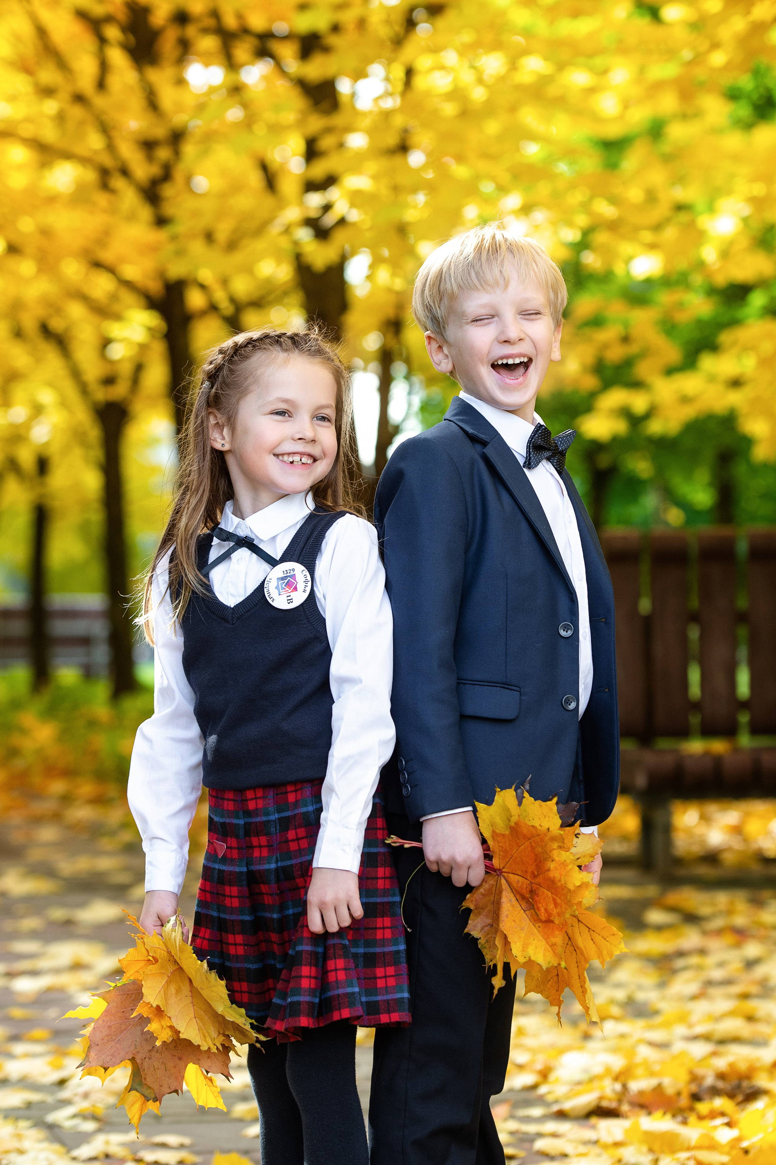 Двое школьников в форме стоят в осеннем парке