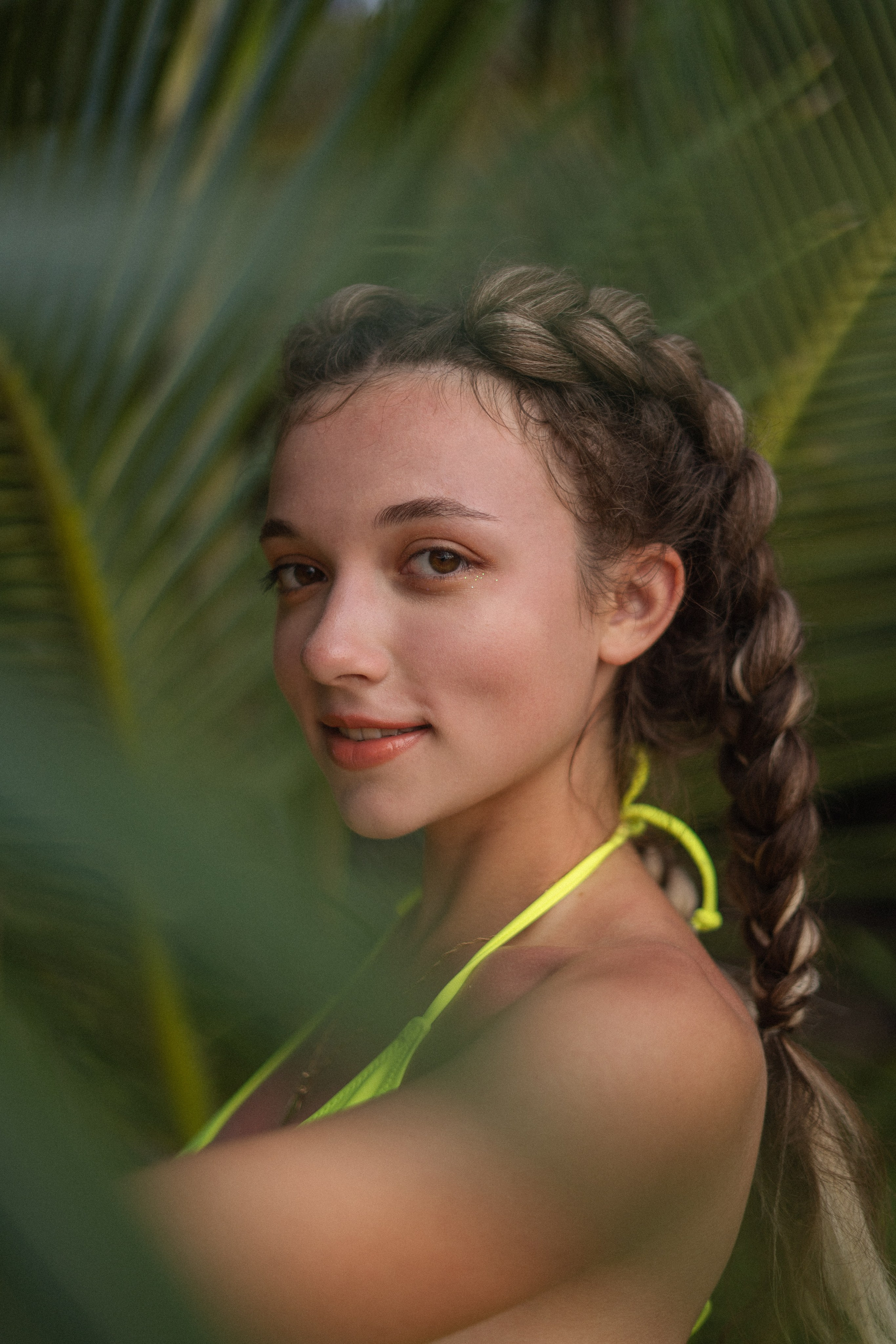 a girl with braids in a yellow swimsuit on the sandy shore