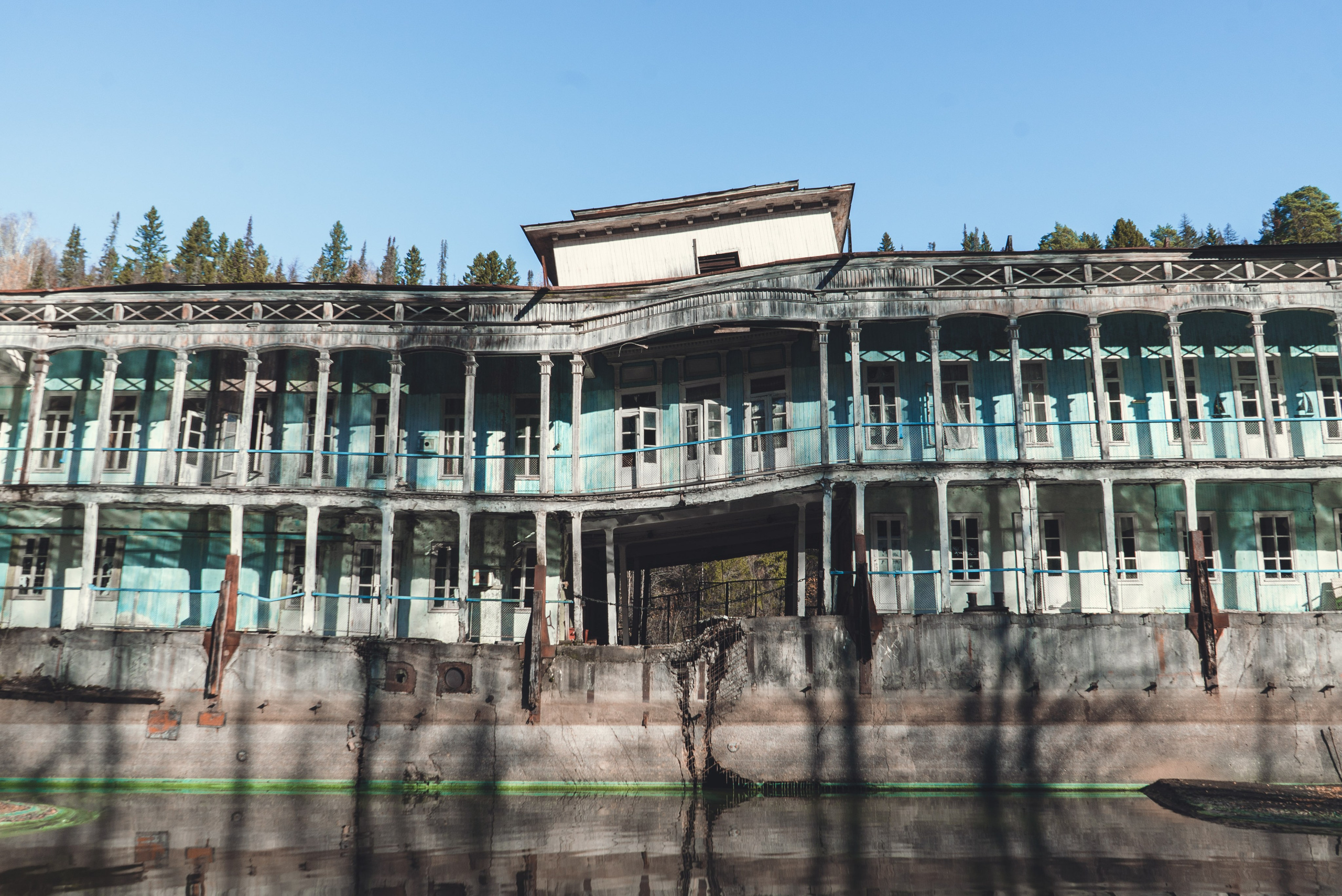 Заброшенное здание, виднеющееся на старинном берегу речной пароход, стоит на водоеме среди густого леса. Его фасад украшен колоннами и балконами, однако здание выглядит ветхим и запущенным: краска облупилась, металл покрыт ржавчиной. Вокруг голые деревья и хвойные леса, что создает ощущение уединенности и застенчивости.