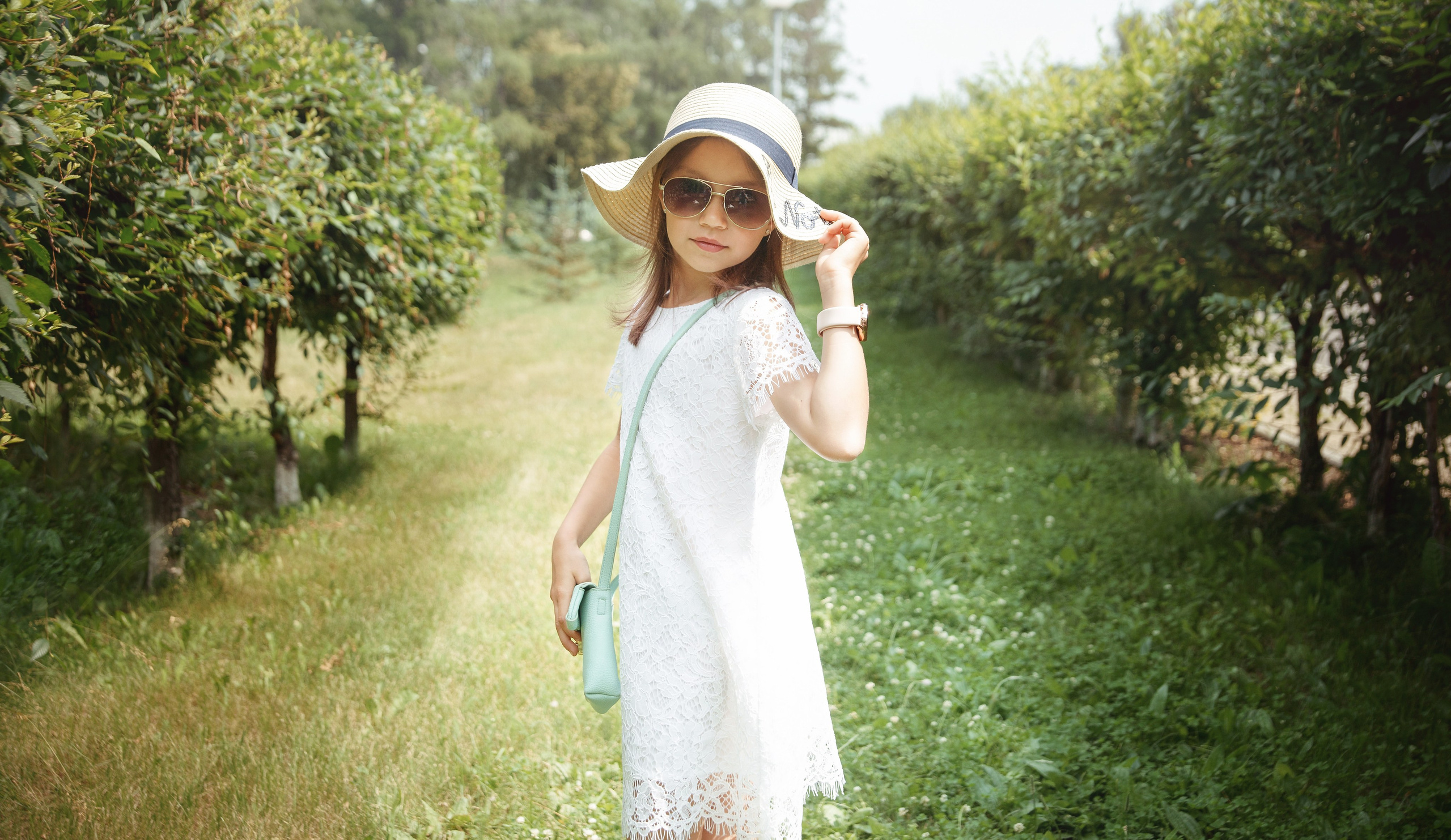 Детская фотосессия летом - девочка стоя держит шляпу