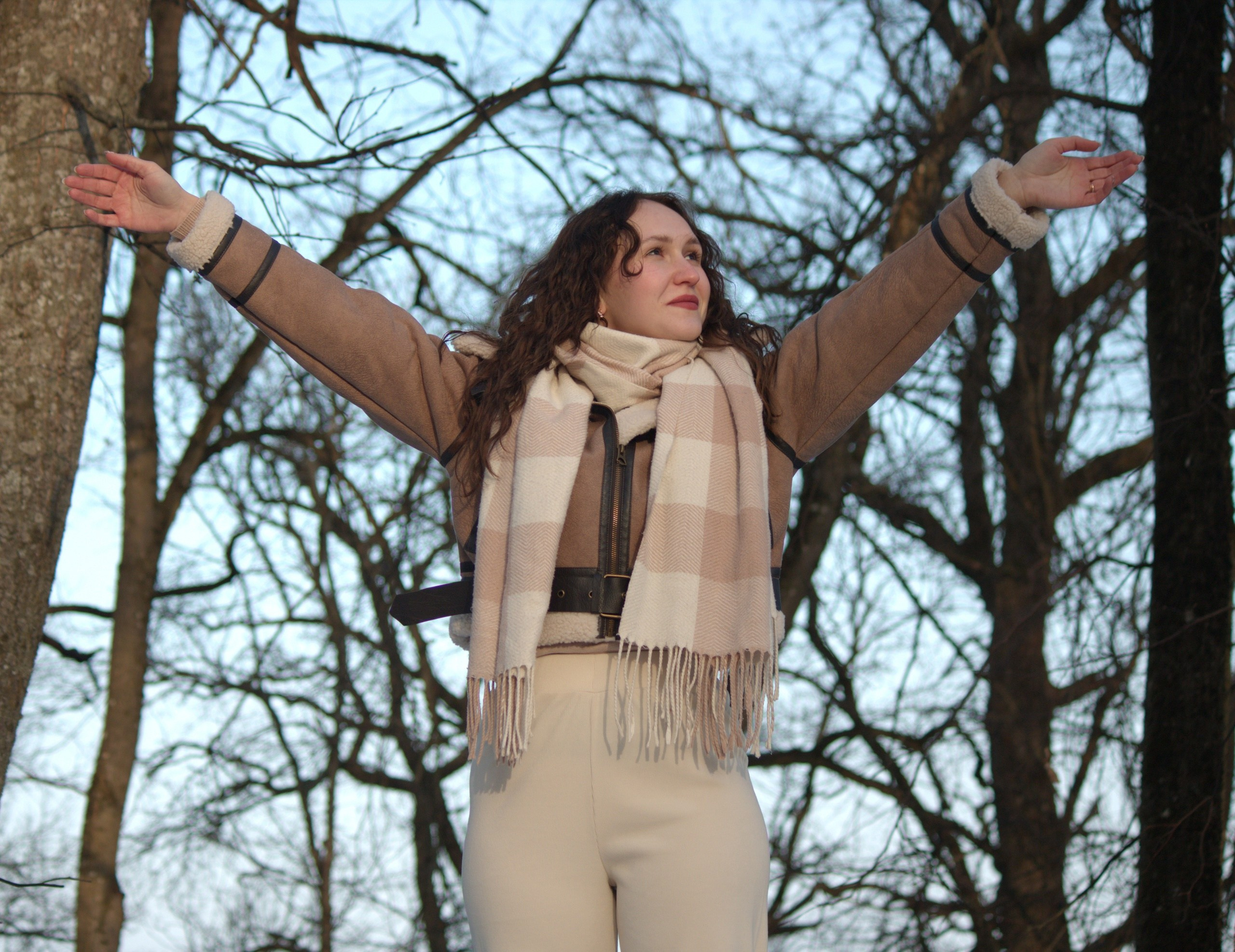 девушка поднимает руки к небу и радуется приходу весны