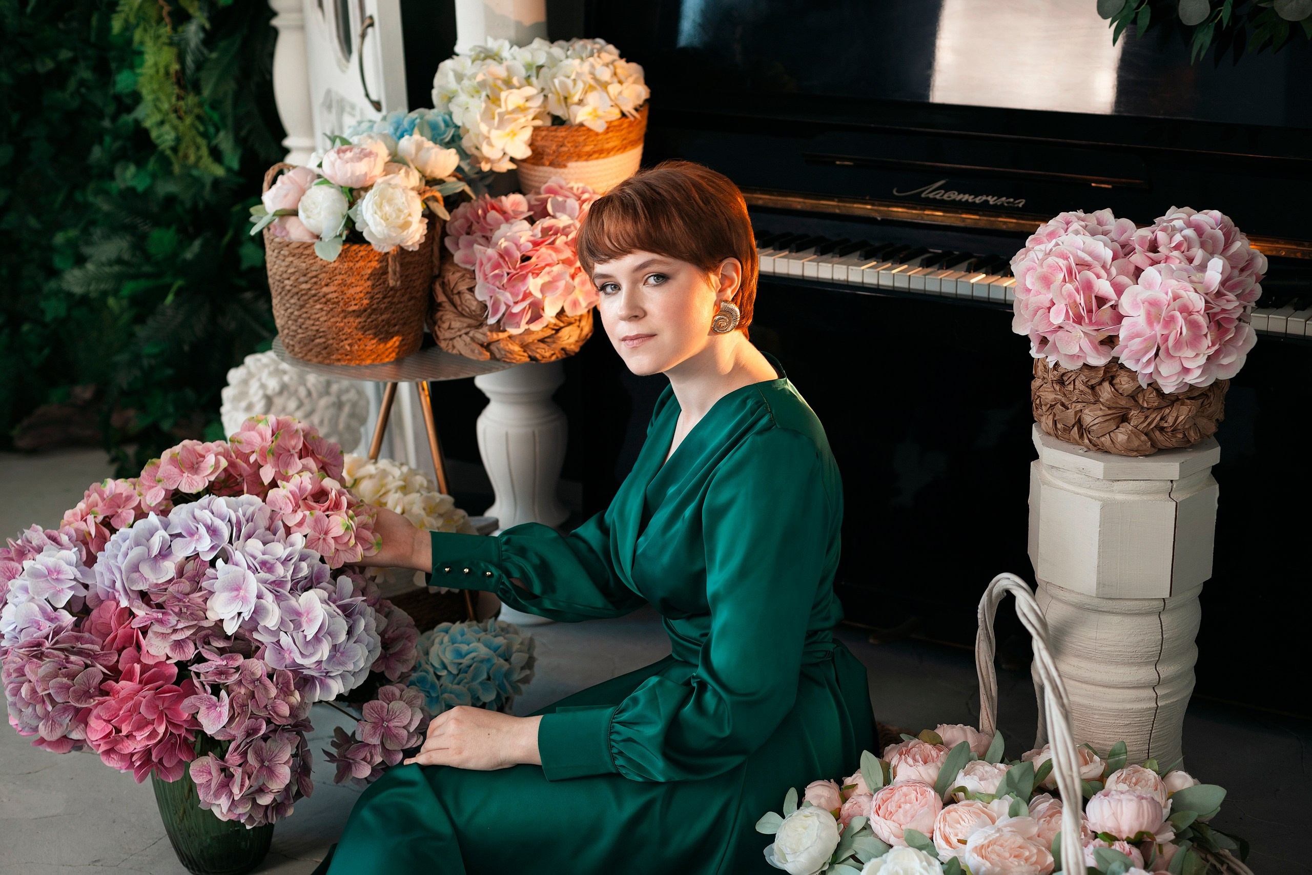 Весенняя женская фотосессия девушки в зелёном платье на фоне цветочных корзин