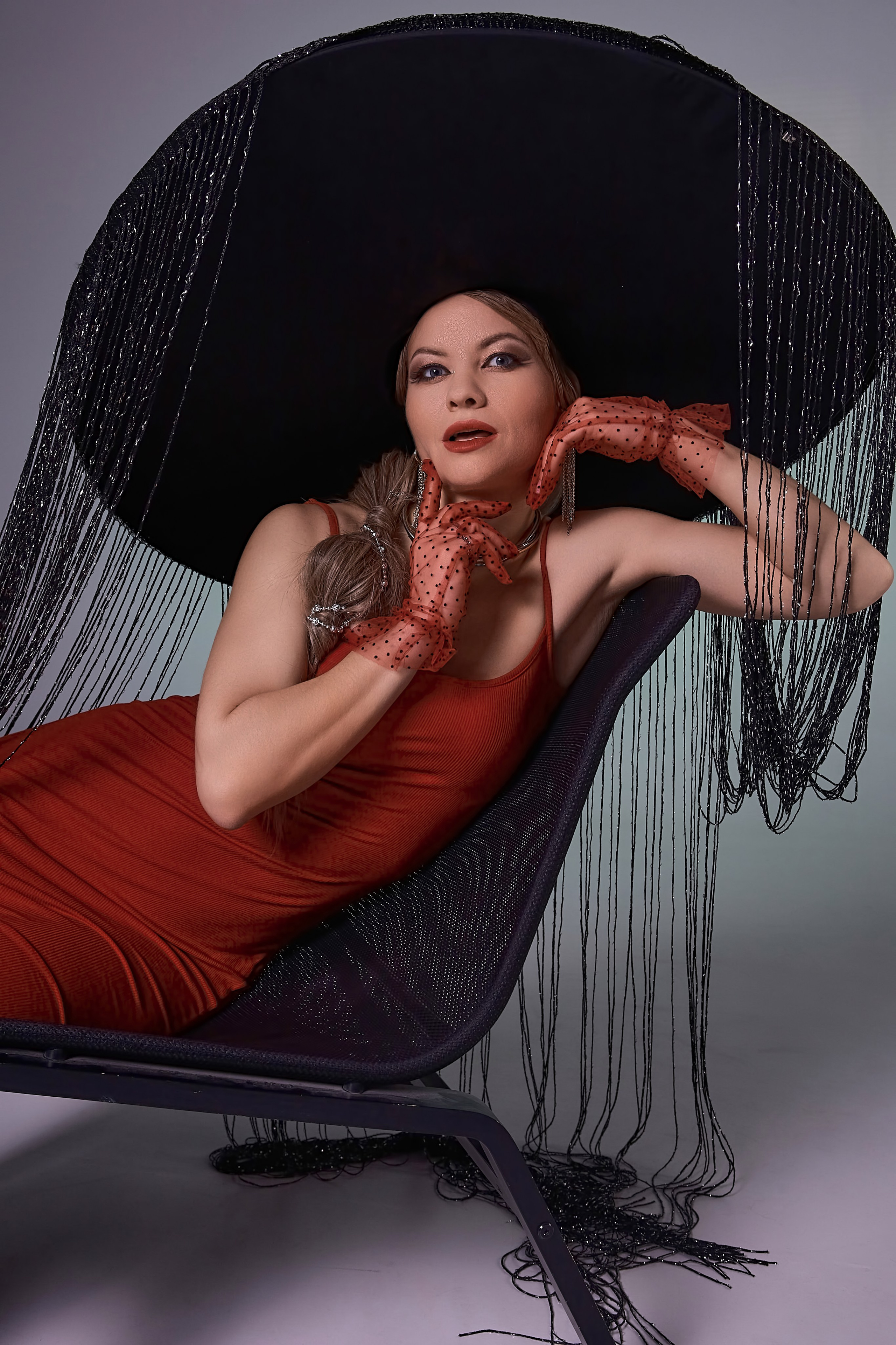 Студийный портрет девушки в красном платье и шляпе с широкими полями