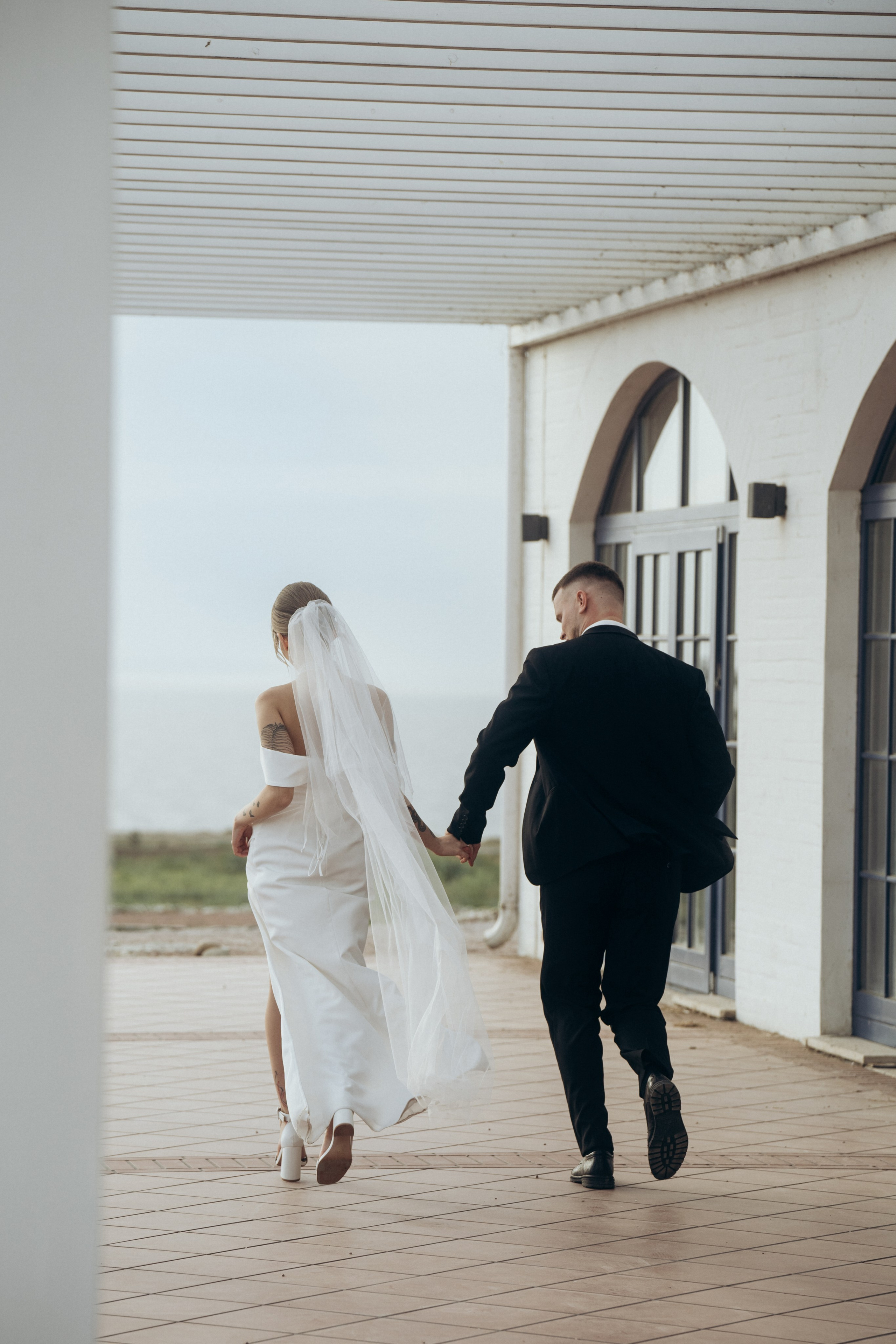 Жених и невеста бегут, фотография со спины, съёмка была проведена в локациях Темрюка, в поместье Голубицкое, Краснодарский край