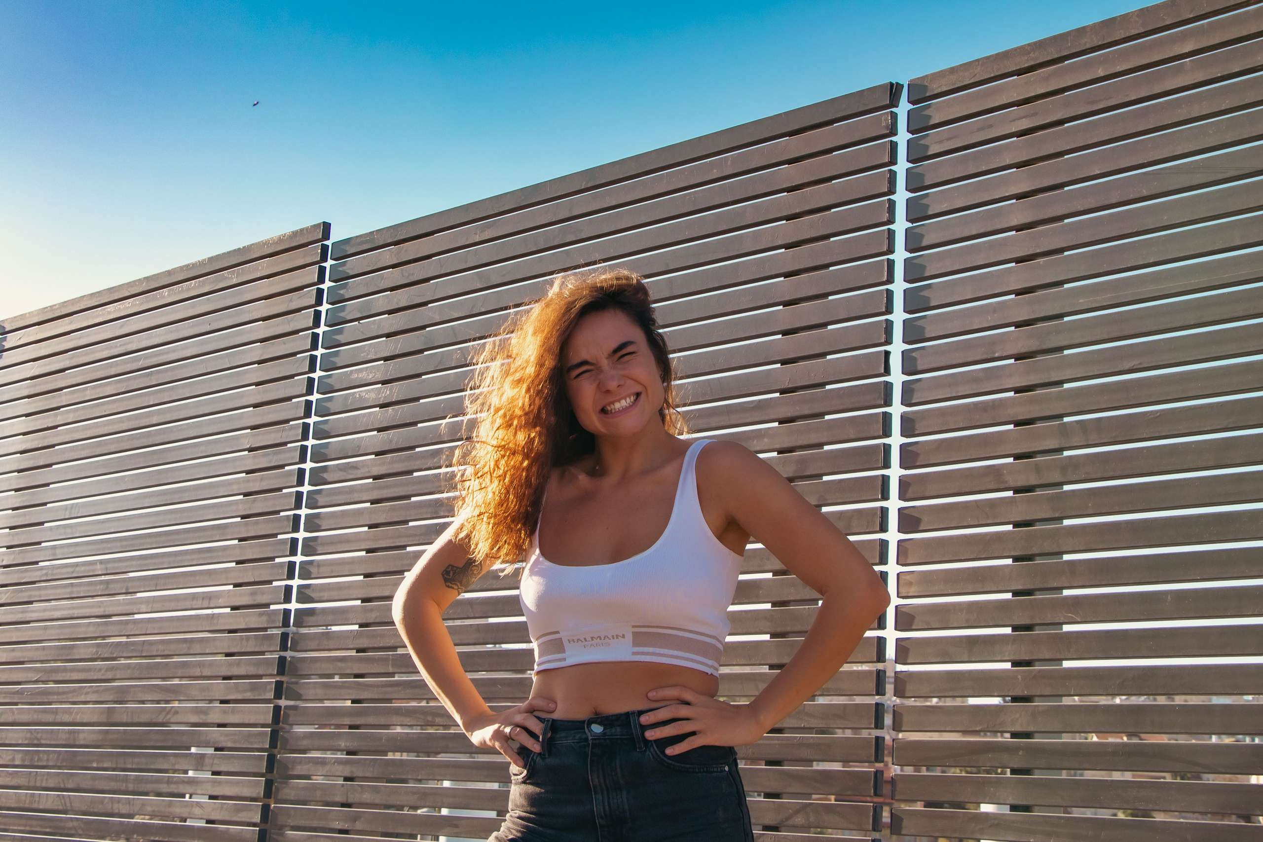 девушка стоит под солнцем с руками на поясе