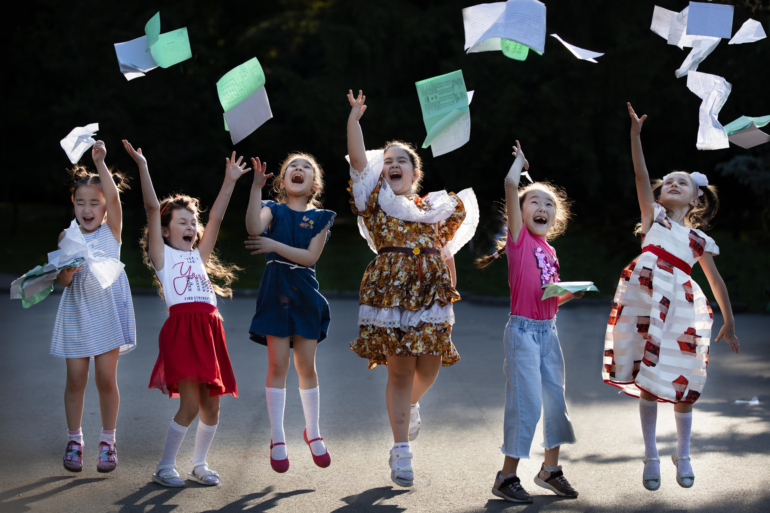 Счастливые школьники бросают тетради вверх