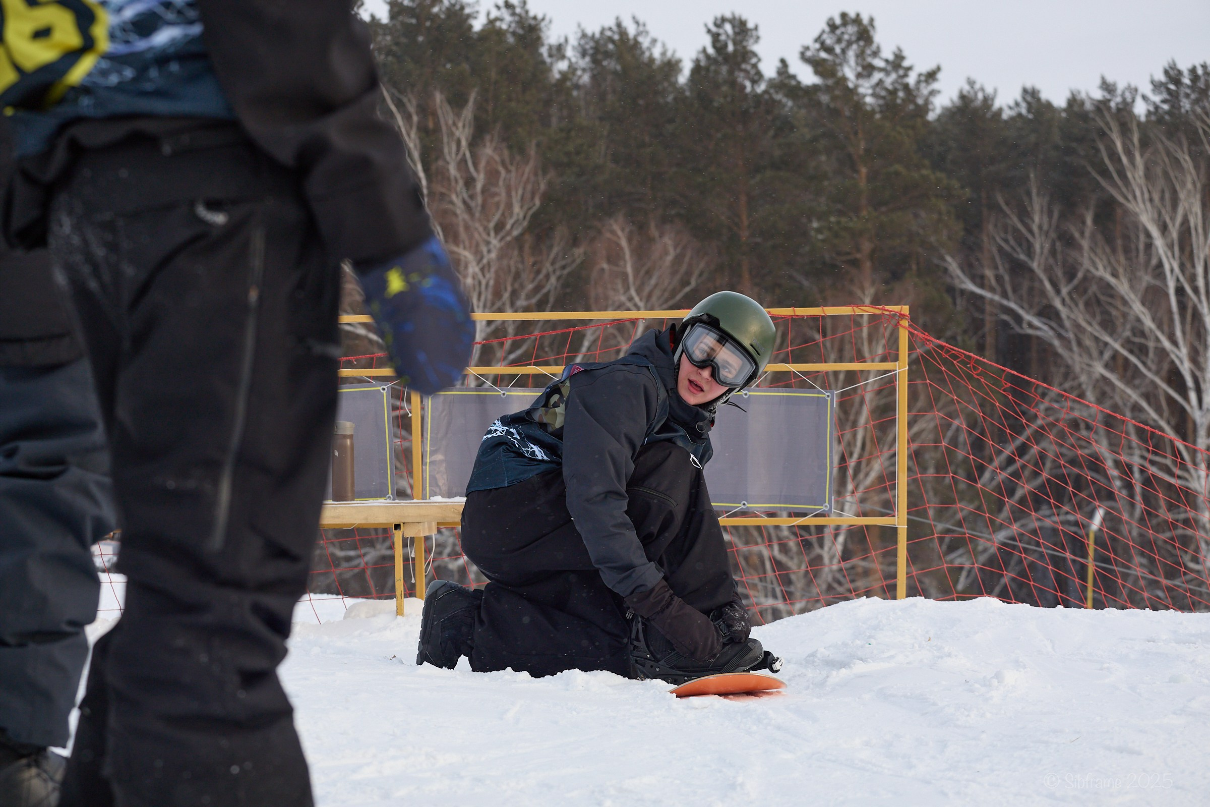 Участник соревнований пристегивается к сноуборду