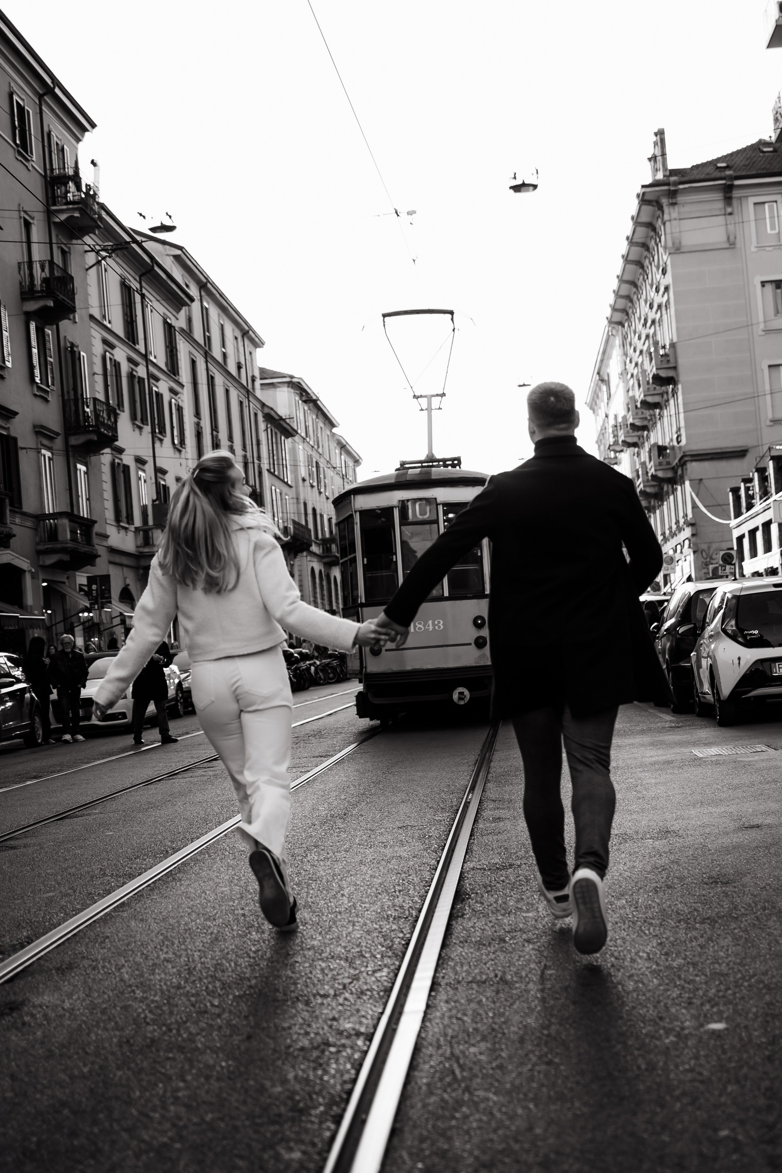 Чёрно-белое фото пары на фоне трамвайных путей в городе