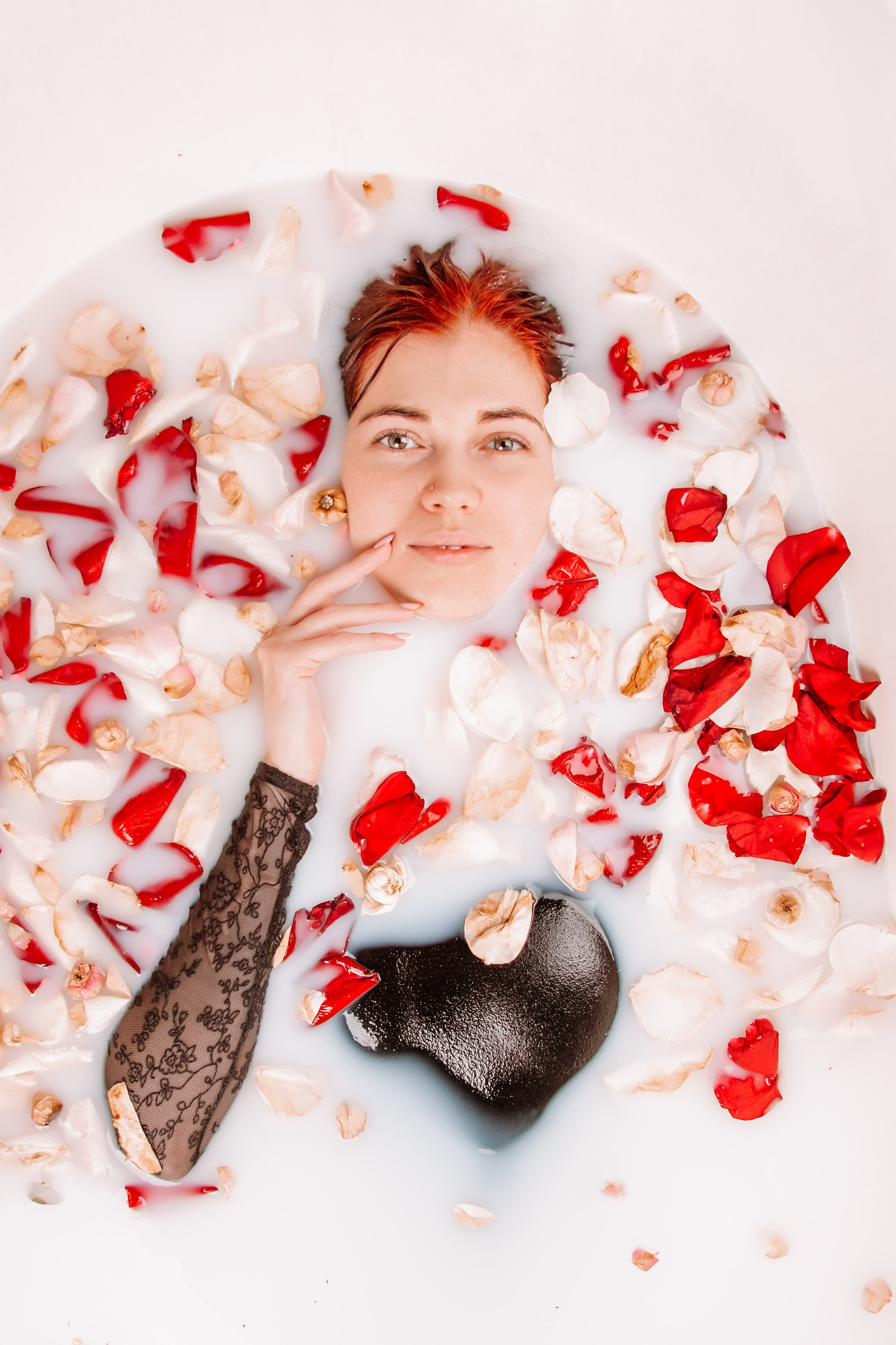 Девушка в ванной и молоке окруженная лепестками роз. 