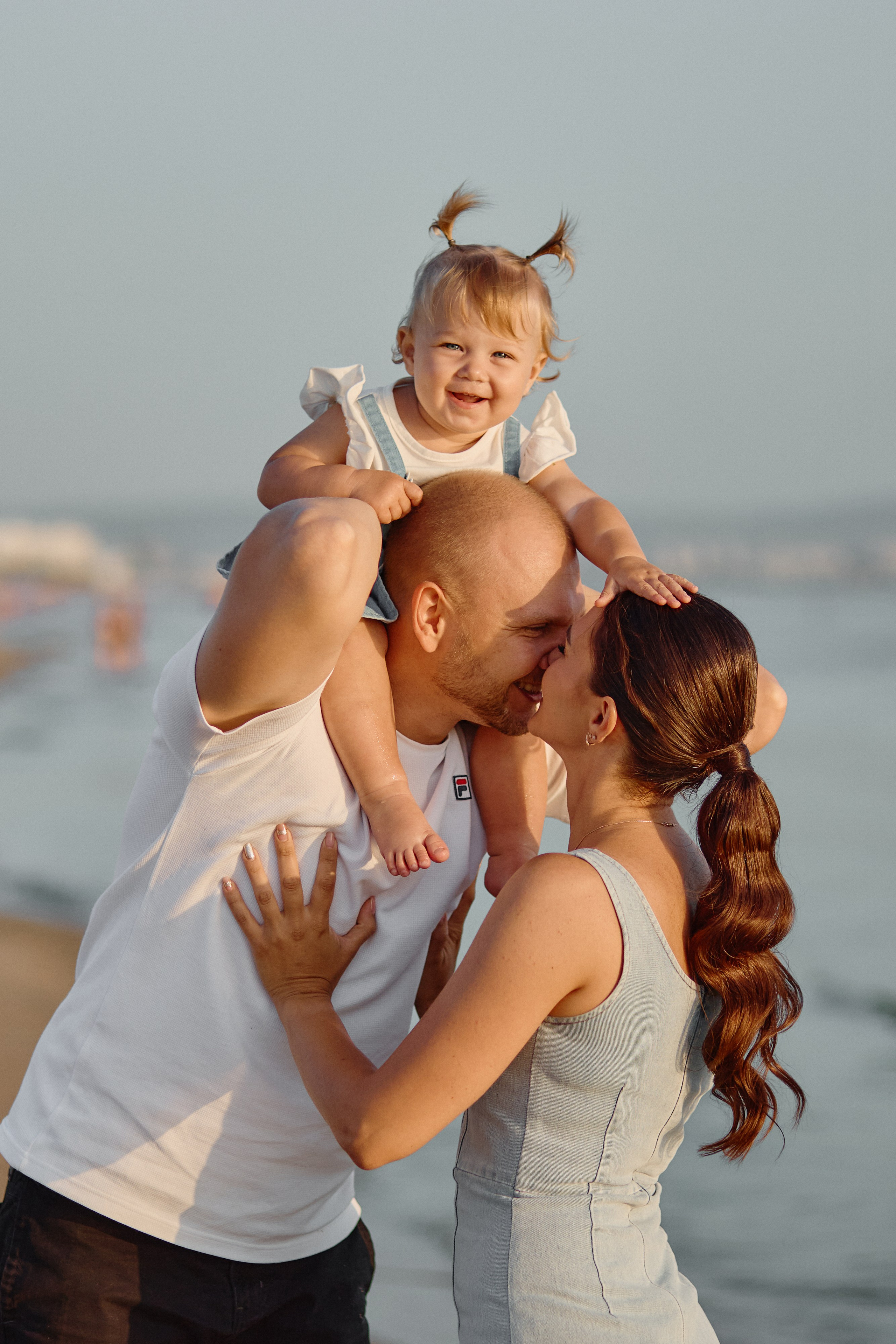 Родители целуются, а дочь сидит на плечах у отца