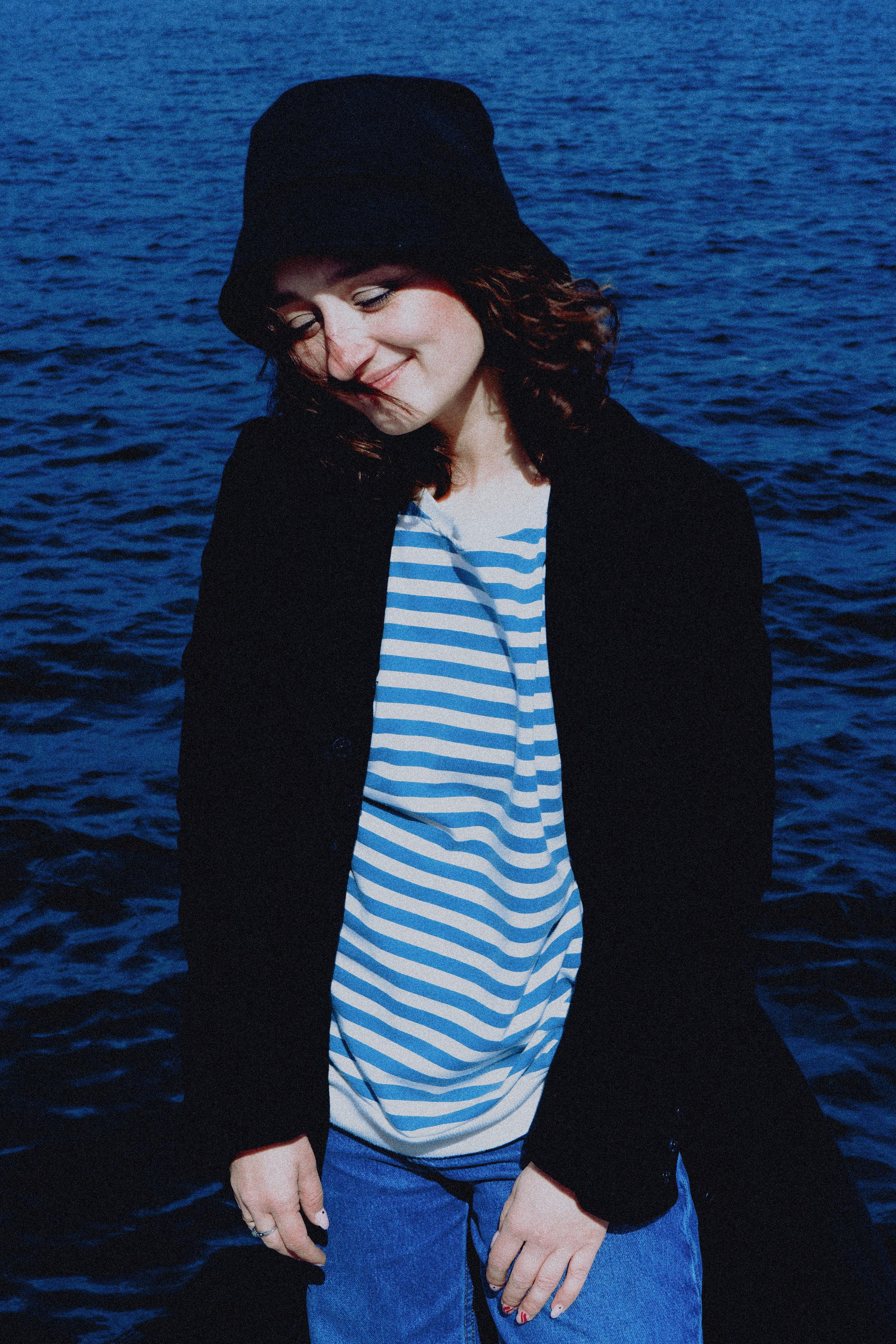 Модель в тельняшке стоит на переднем плане на фоне реки