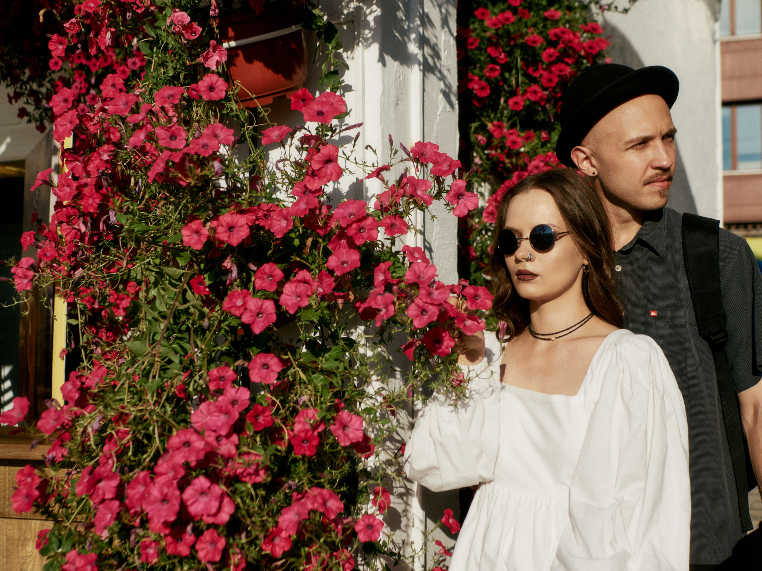 Элегантная пара на фоне ярких розовых цветов, создающая атмосферу летней романтики