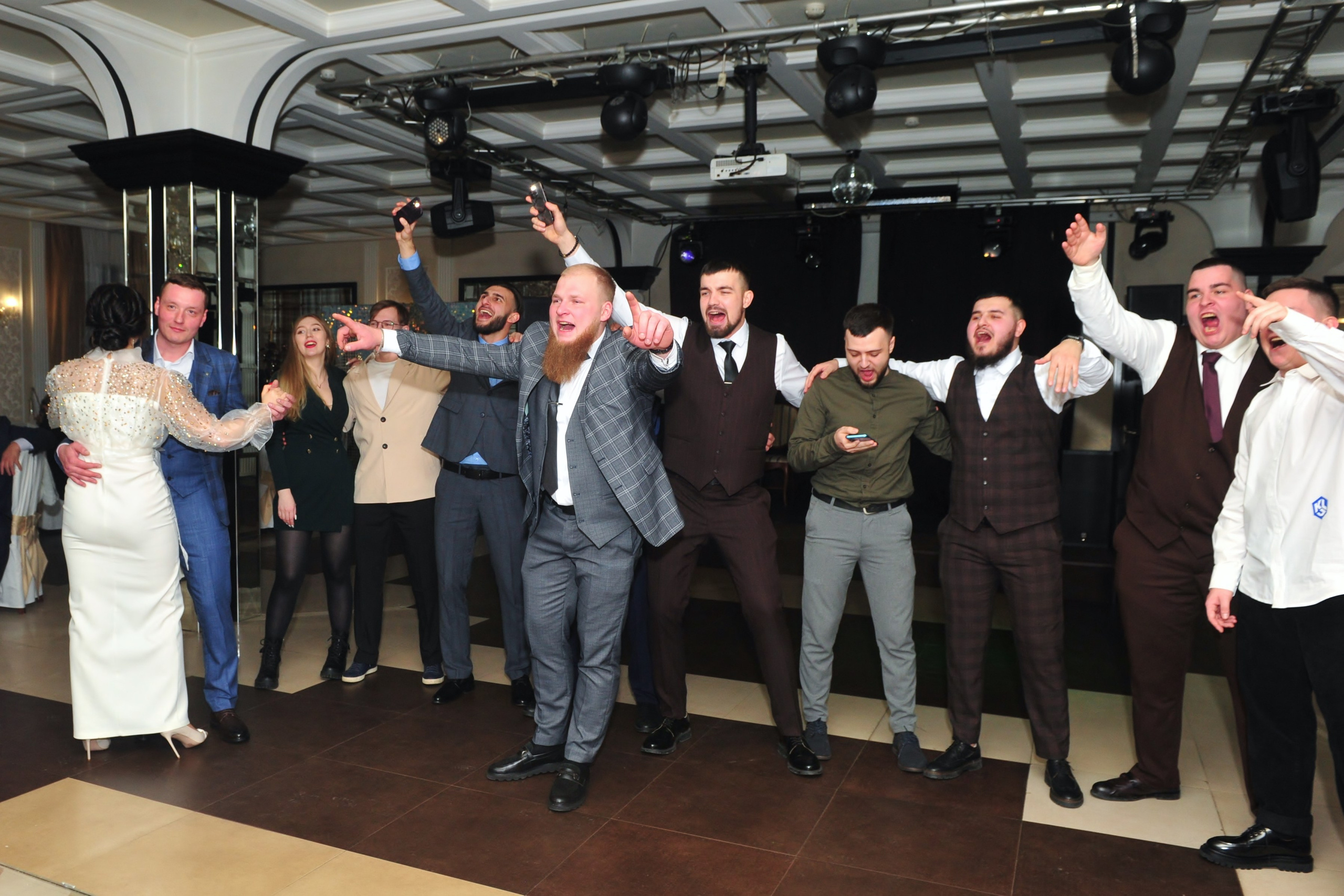 Гости поздравляют молодоженов на свадебном банкете в ресторане