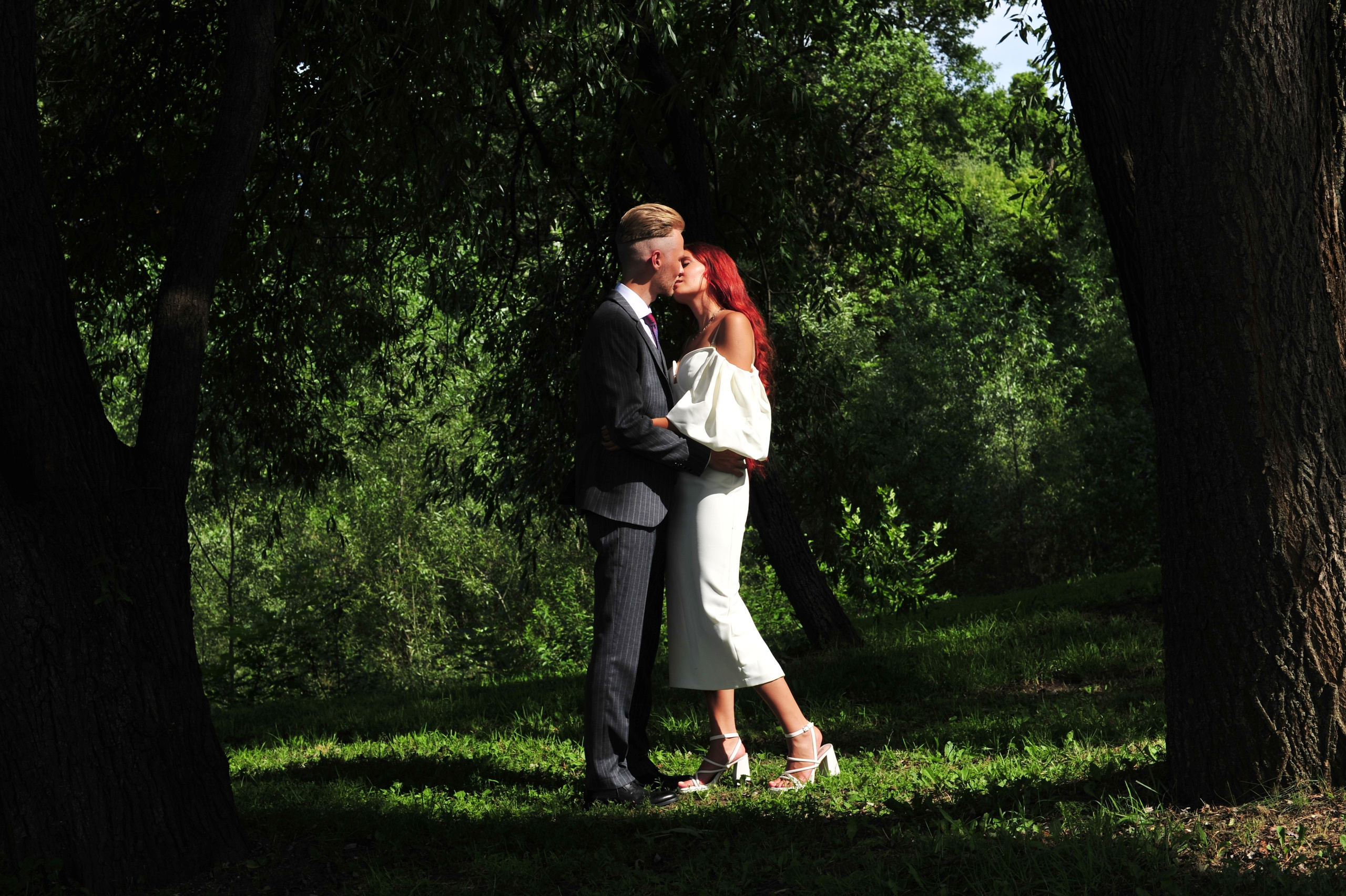 Свадьба в Царицыно летом, жених и невеста обнимаются на лесной поляне среди деревьев