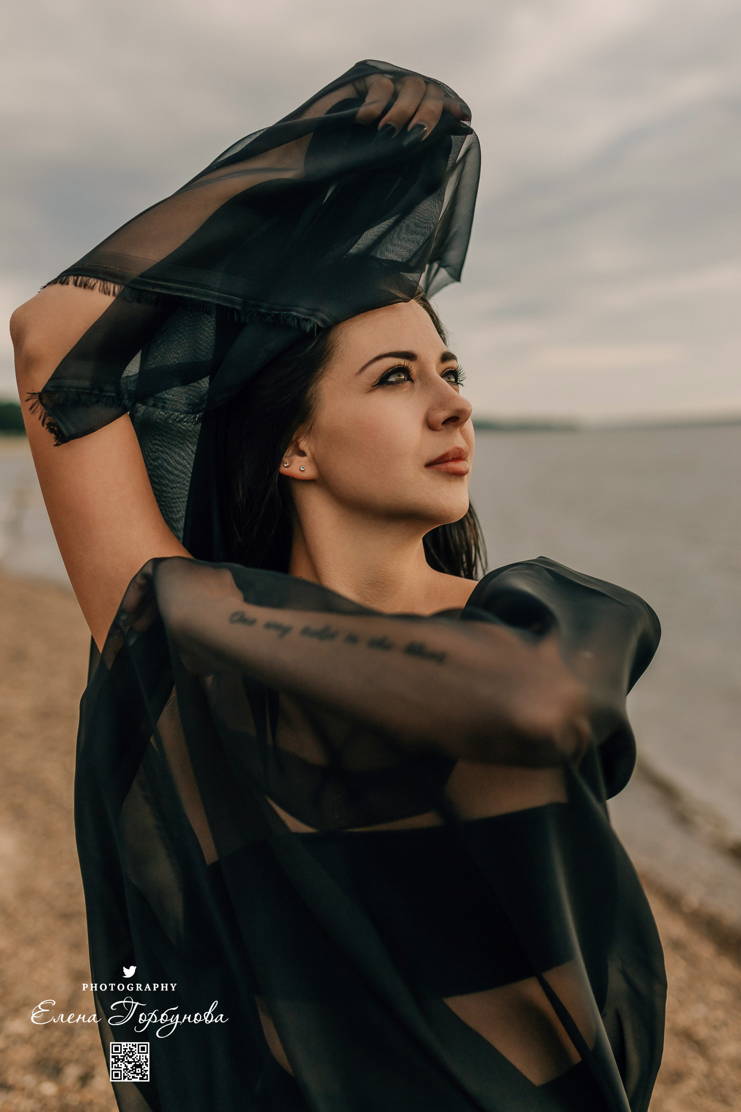 Фотосессия с черной тканью. Легкая черная вуаль летит на вертру. Фотосессия у реки черная серия с тканью. Девушка укуталась в черную ткань. Прогулка по набережной. Песок, речка, модель в черном. Качели над водой, Закат. Девушка лежит на песке. В зеленых деревьях