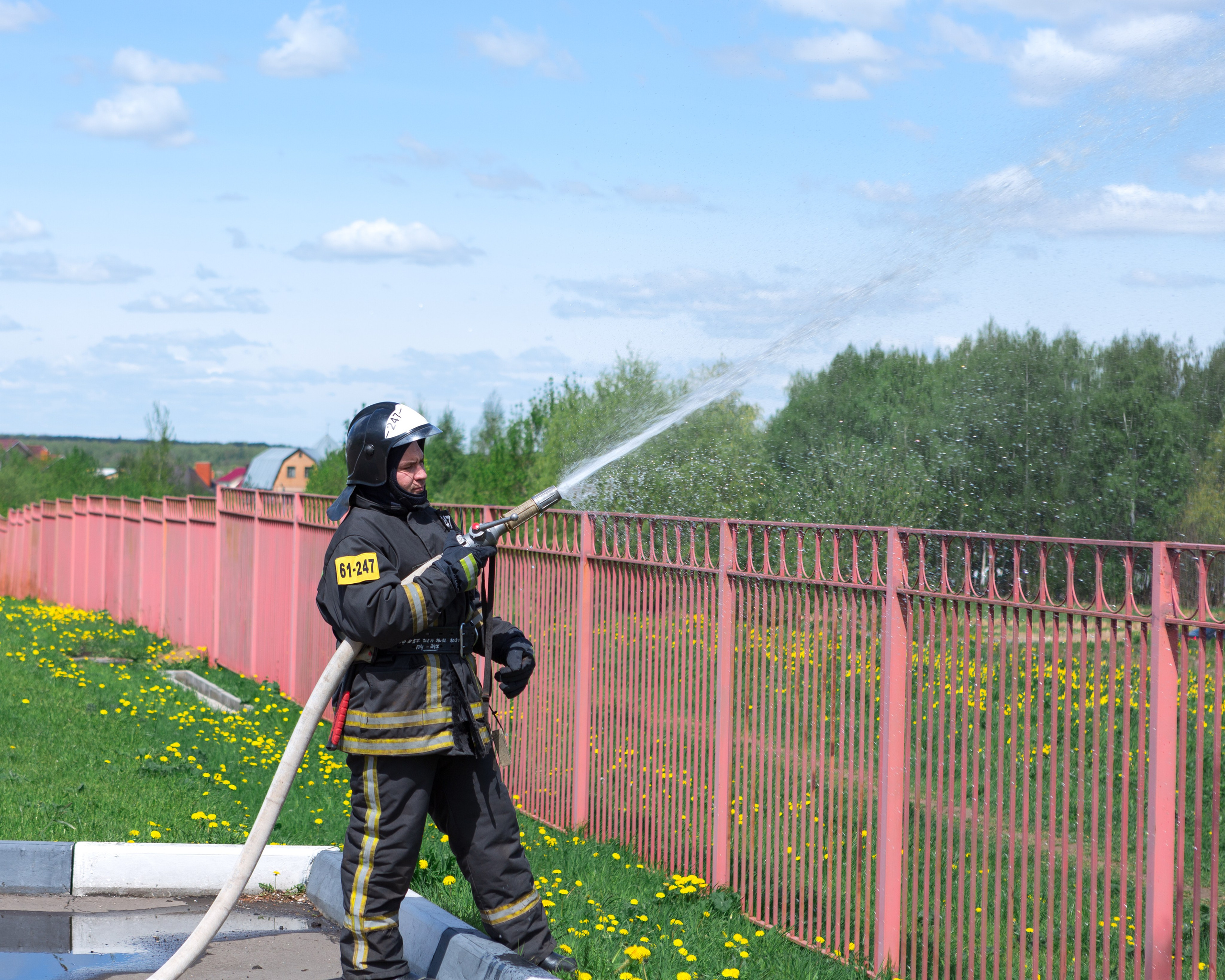 Пожарный поливает из шланга