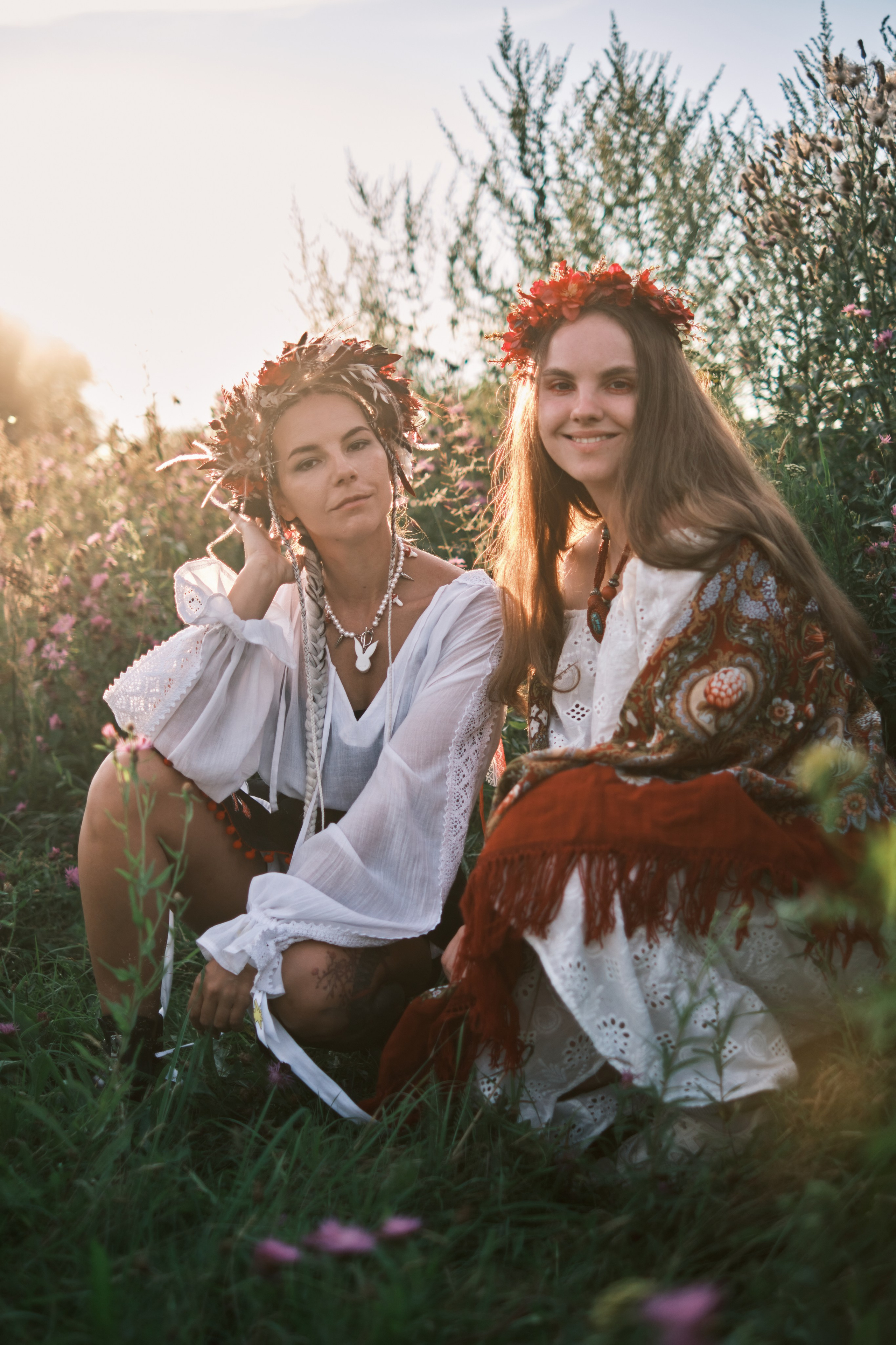 Девушки сидят на фоне заката в костюмах в русском стиле