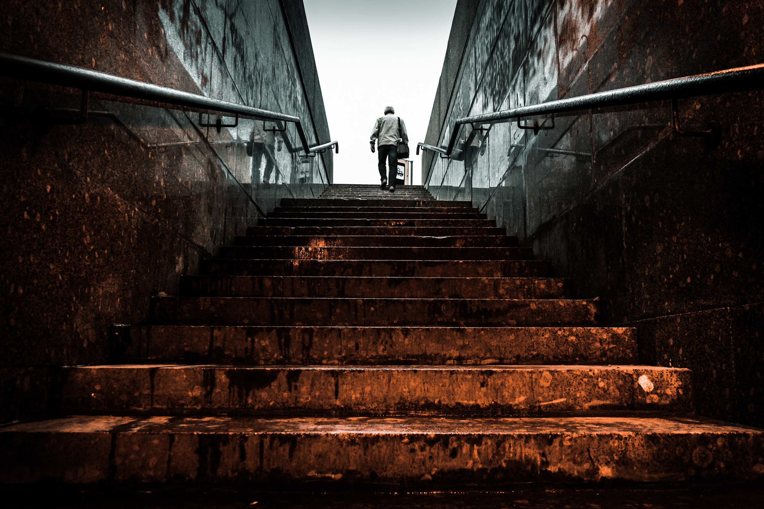 Одинокий мужчина поднимается по широкой лестнице в тёмном урбанистическом пространстве, Санкт-Петербург, street photography, фотограф Мальцев Евгений.