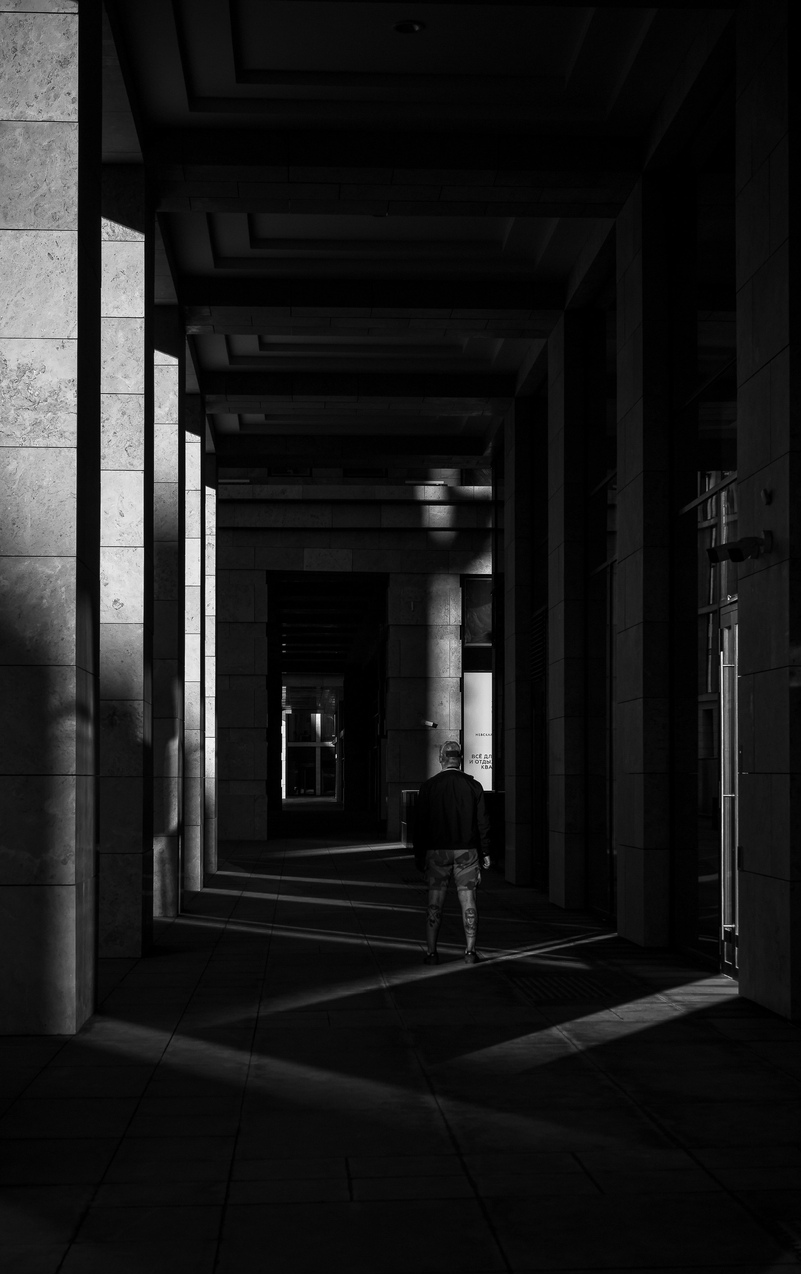 Невская Ратуша. Силуэт мужчины в длинном стеклянном коридоре современного здания, чёрно-белое урбан-фото архитектуры Санкт-Петербурга, street-портрет, фотограф Евгений Мальцев Ev Rednix.