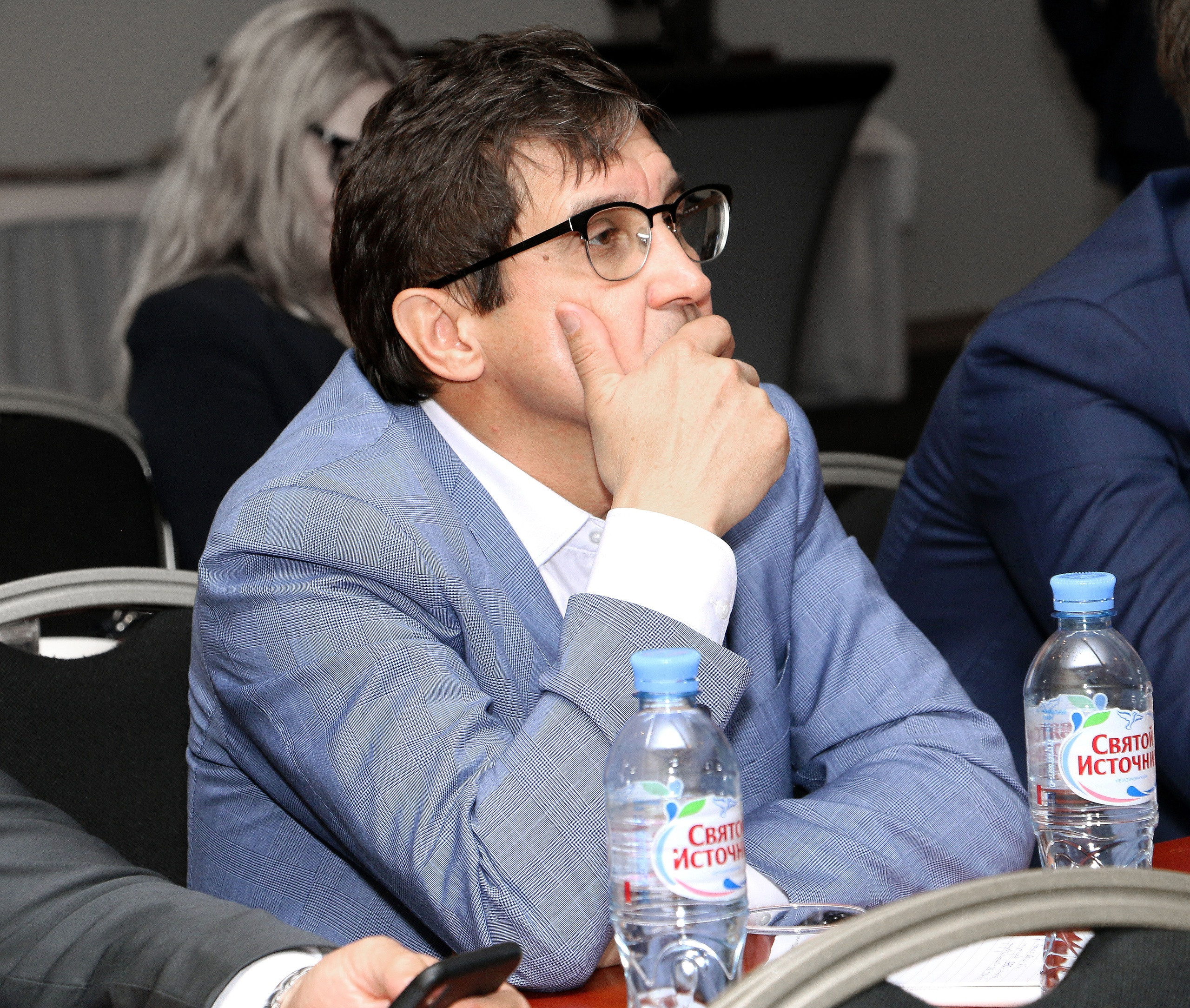 Мужчина слушает докладчика на конференции. Внимательный взгляд и сосредоточенность делового человека