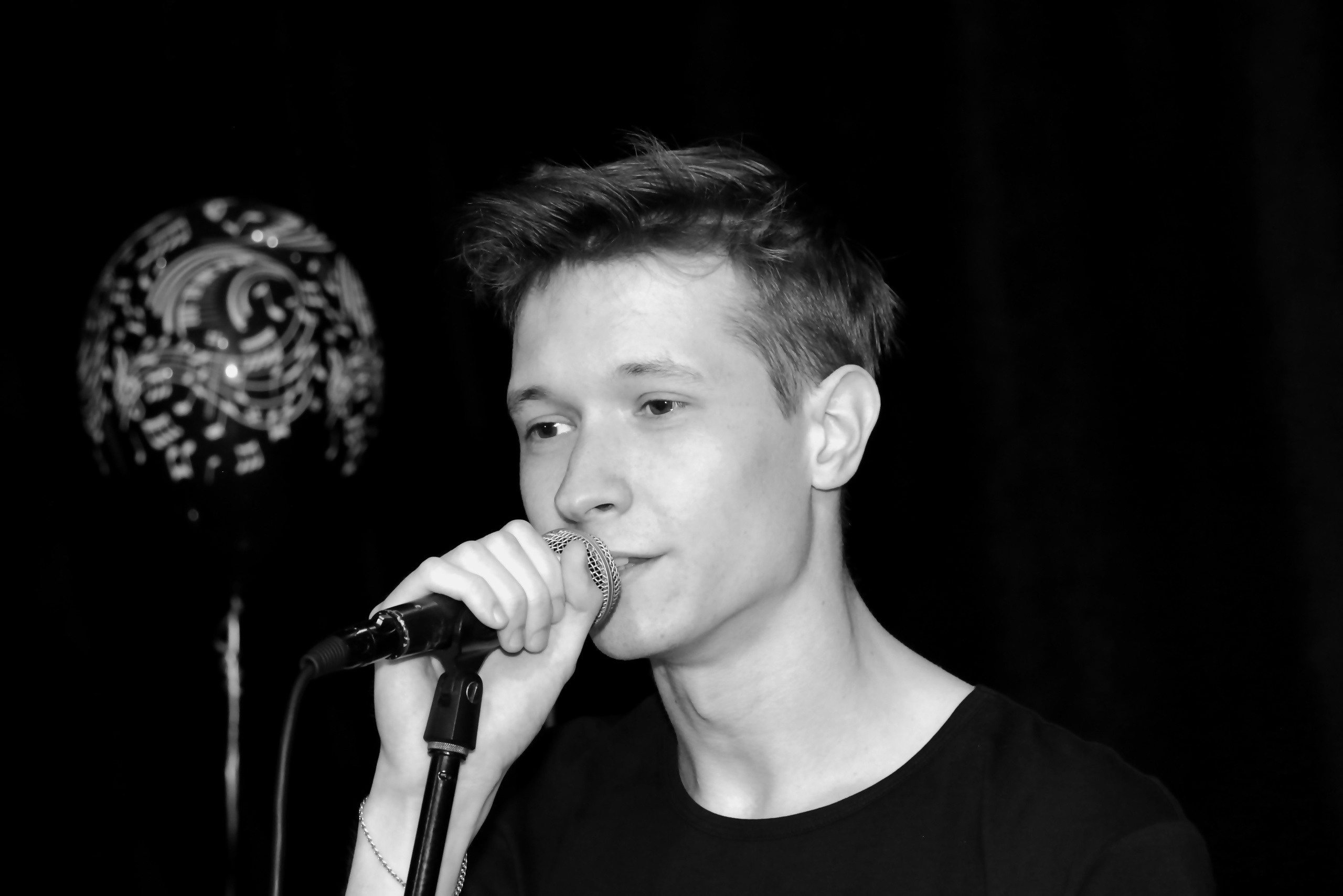 Молодой человек поет на сцене. Сольное выступление