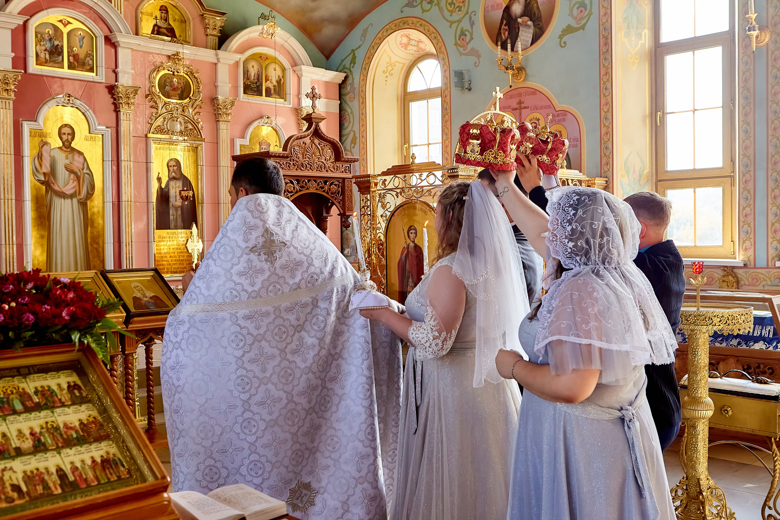 Священник ведет молодых вокруг аналое свидетели несут венцы над главами