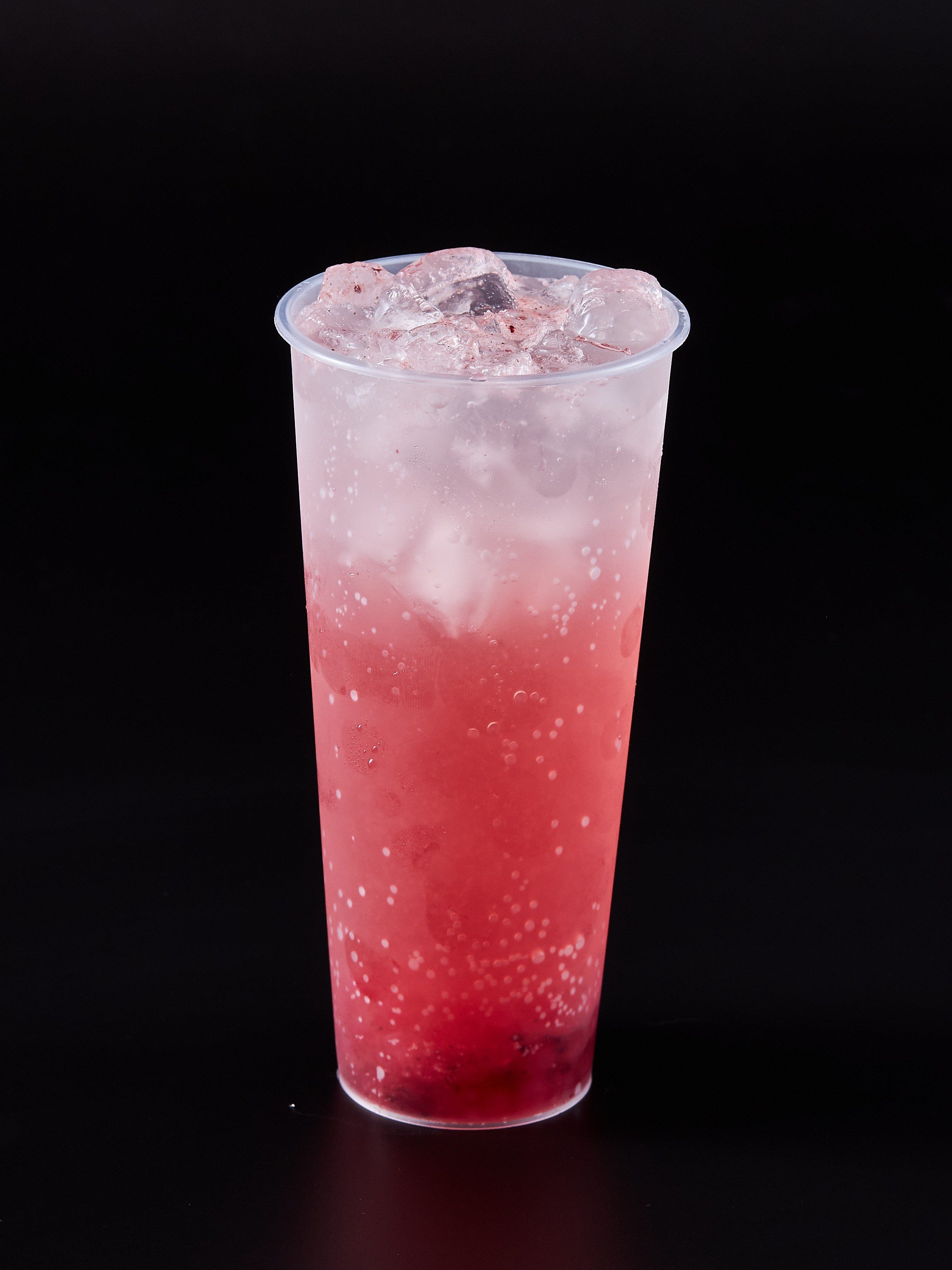 Коктейль в пластиковом стакане красного цвета на черном фоне