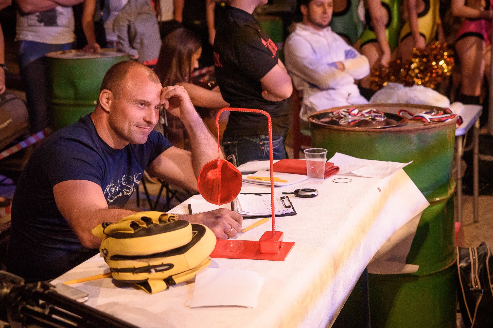 Судья поединка сидит за столом и улыбается 