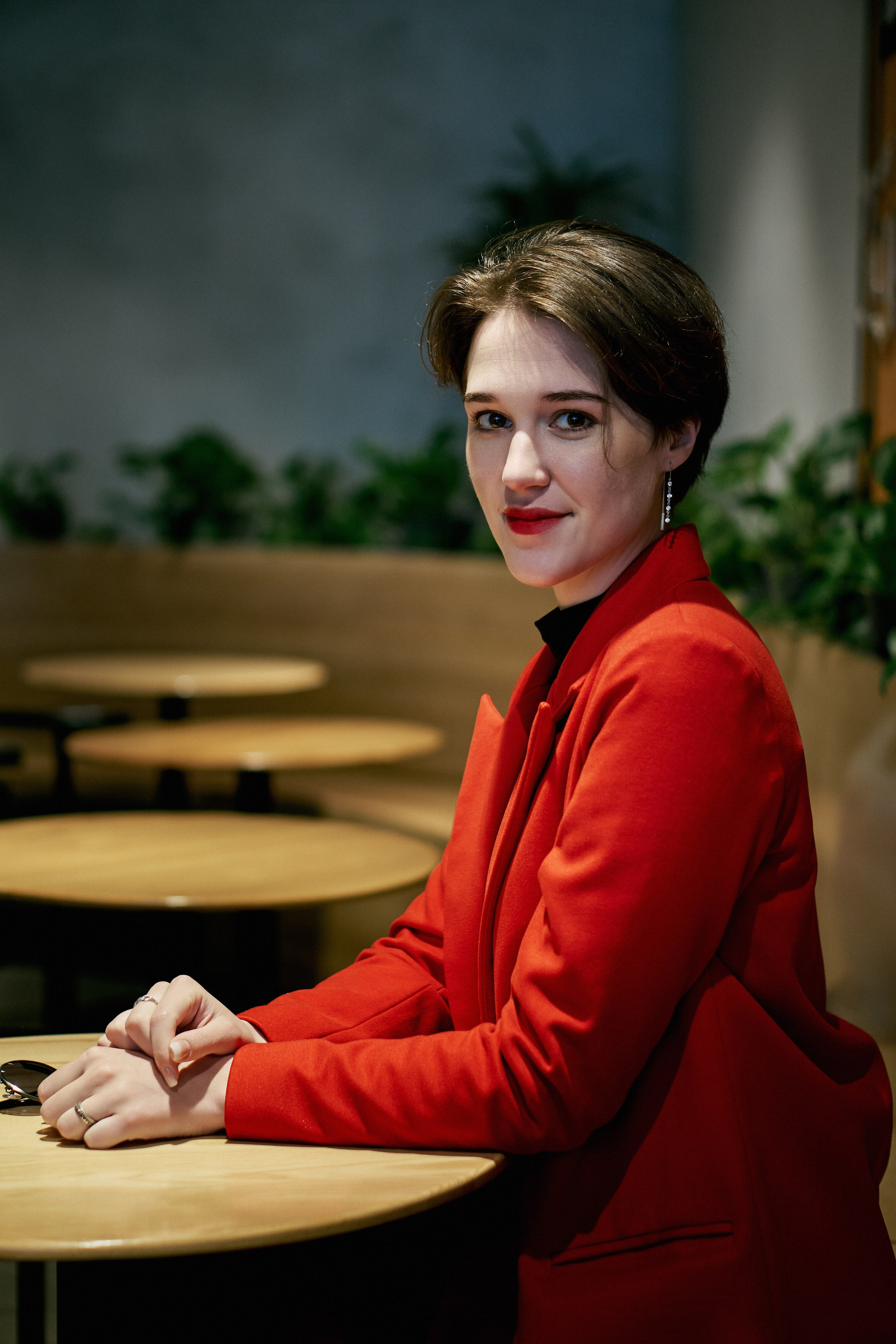 Девушка в красном пиджаке сидит в кафе