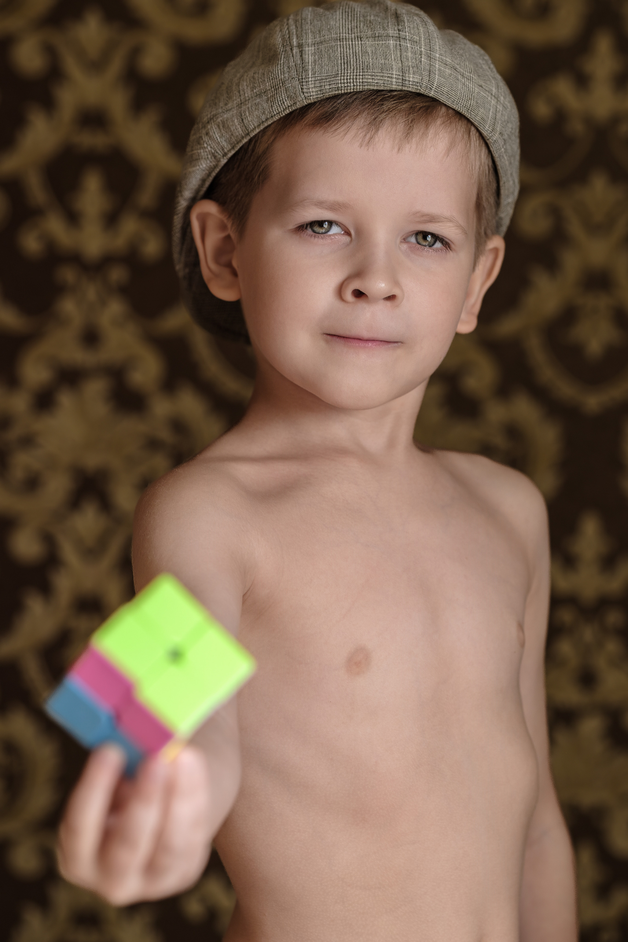 Детский портрет, мальчик показывает кубик Рубика, он в кепке