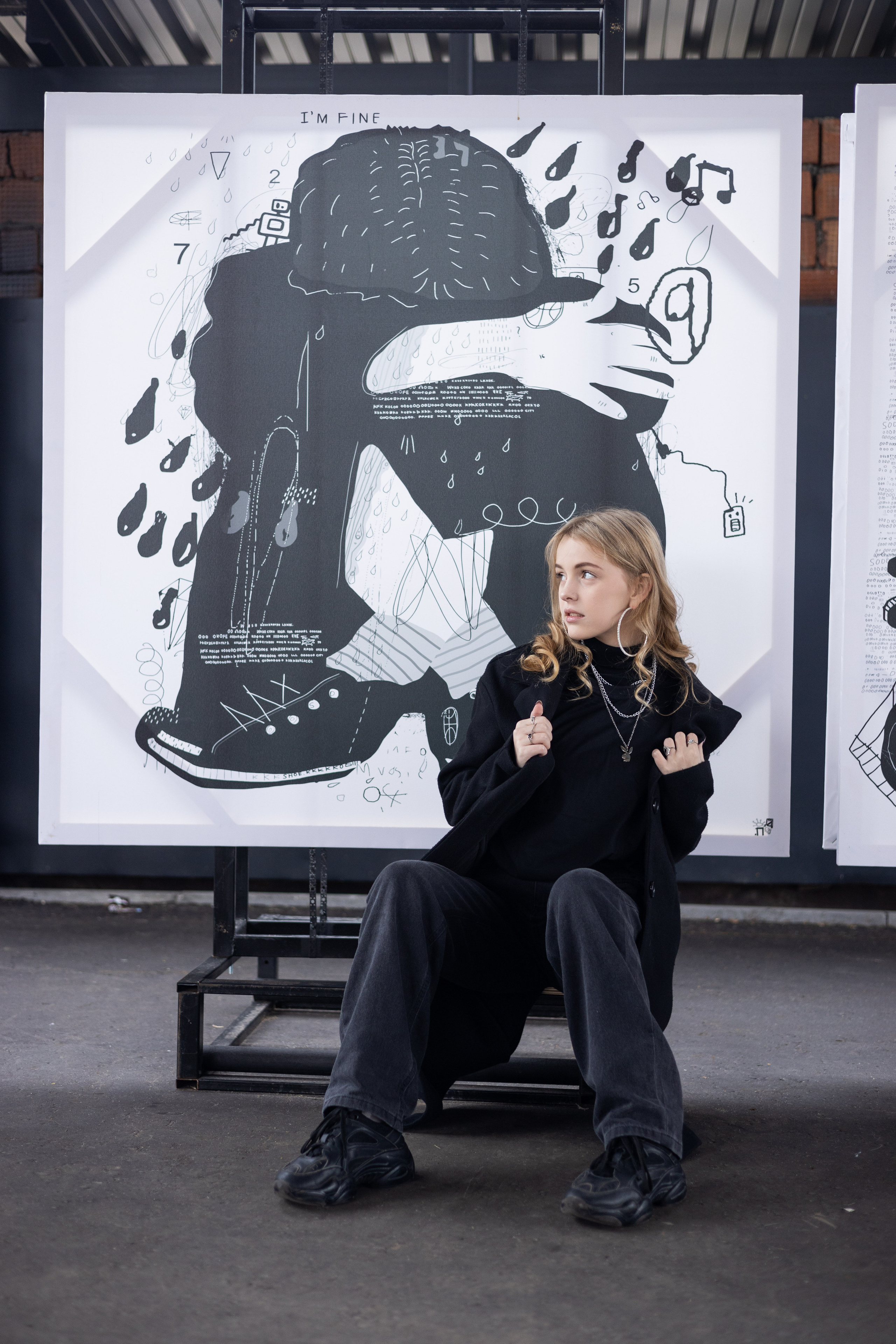 Ученица Коломенской школы сидит в чёрном пальто на фоне картины.