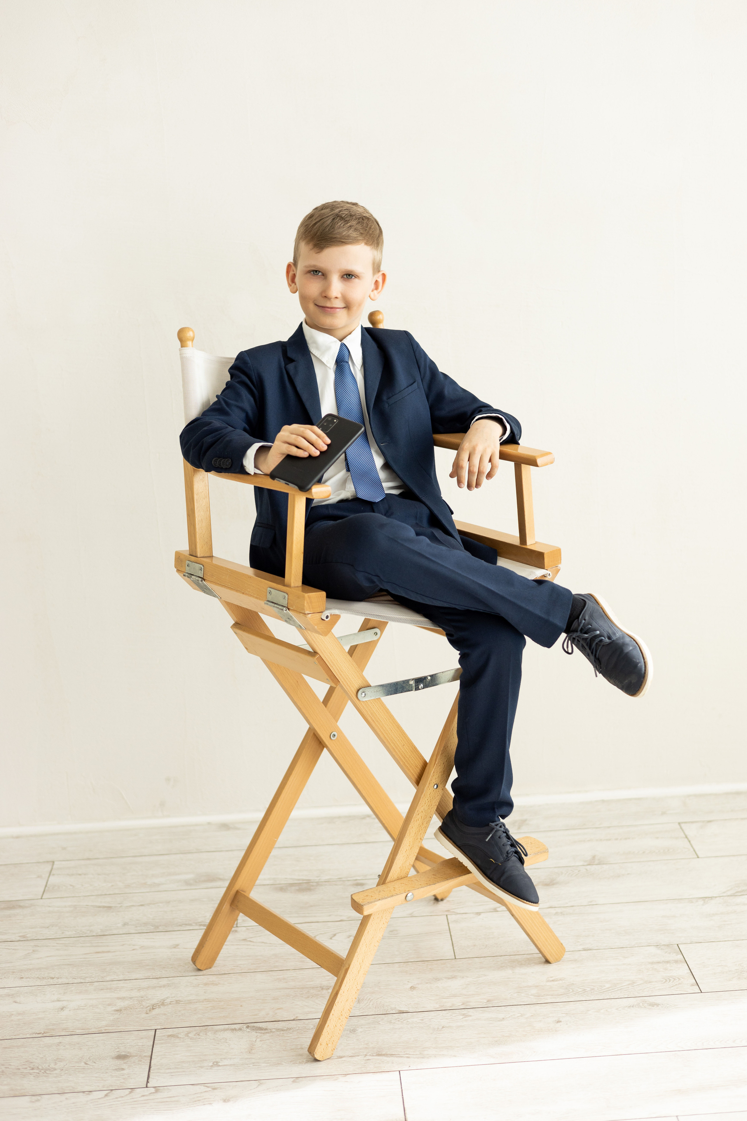 Ученик средней школы на стуле в студии позирует для школьного альбома.