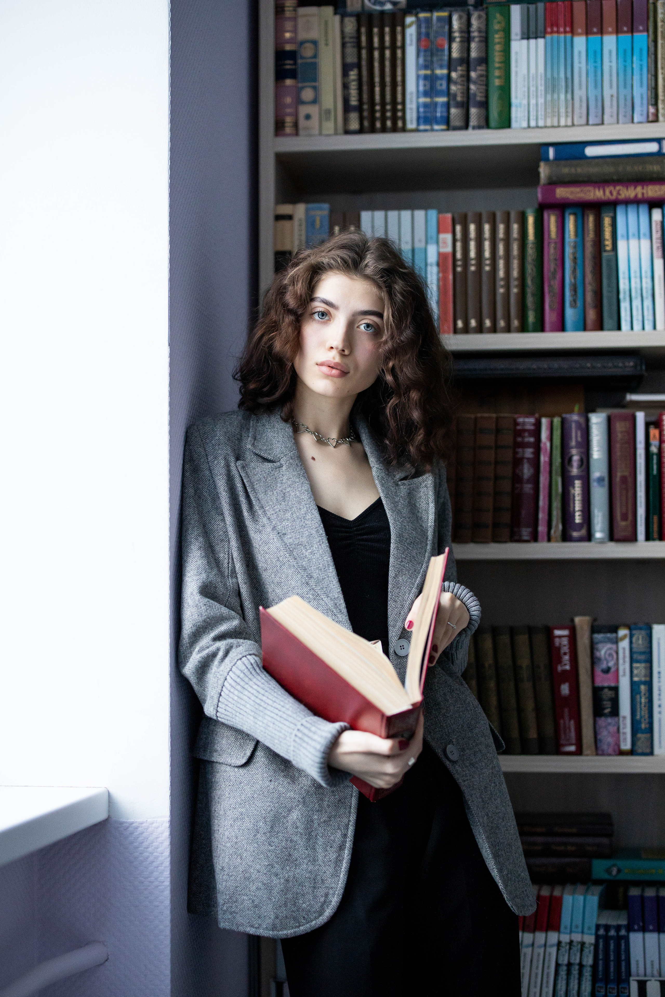 Ученица одиннадцатого класса у окна в библиотеке.