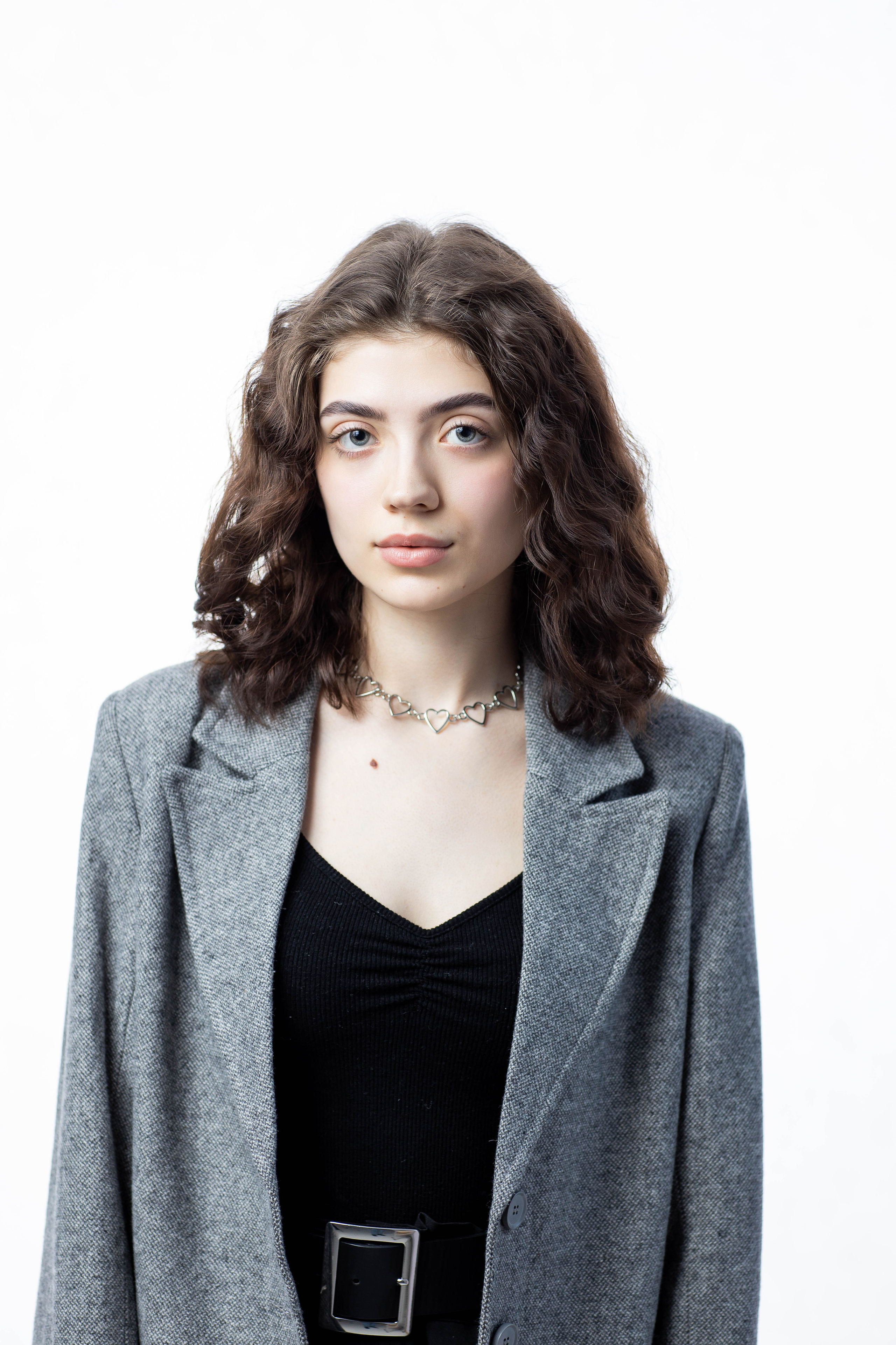 Портрет школьницы с кудрявыми волосами на белом фоне.